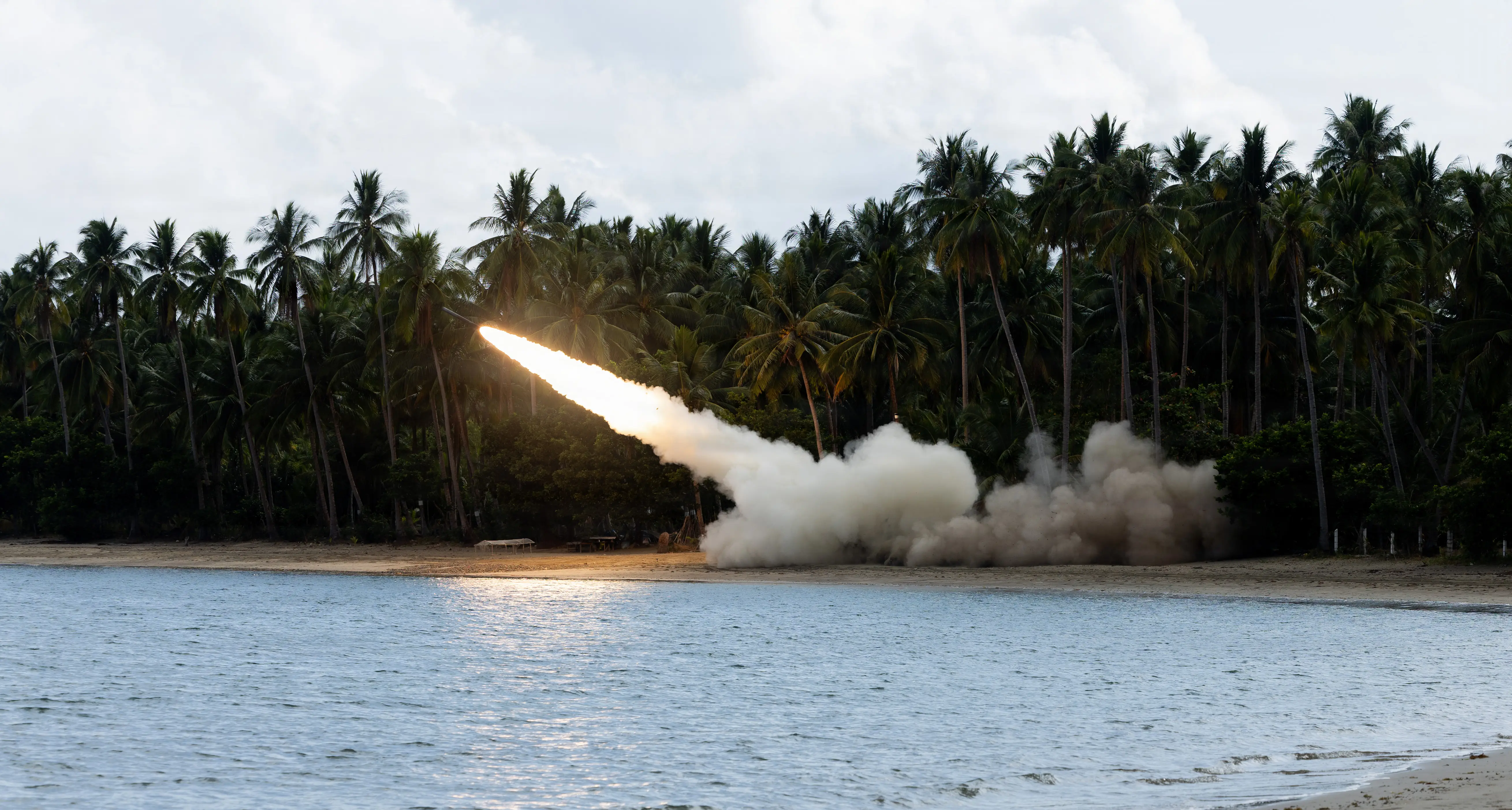 A US Army M142 High Mobility Artillery Rocket System fires on a beach.