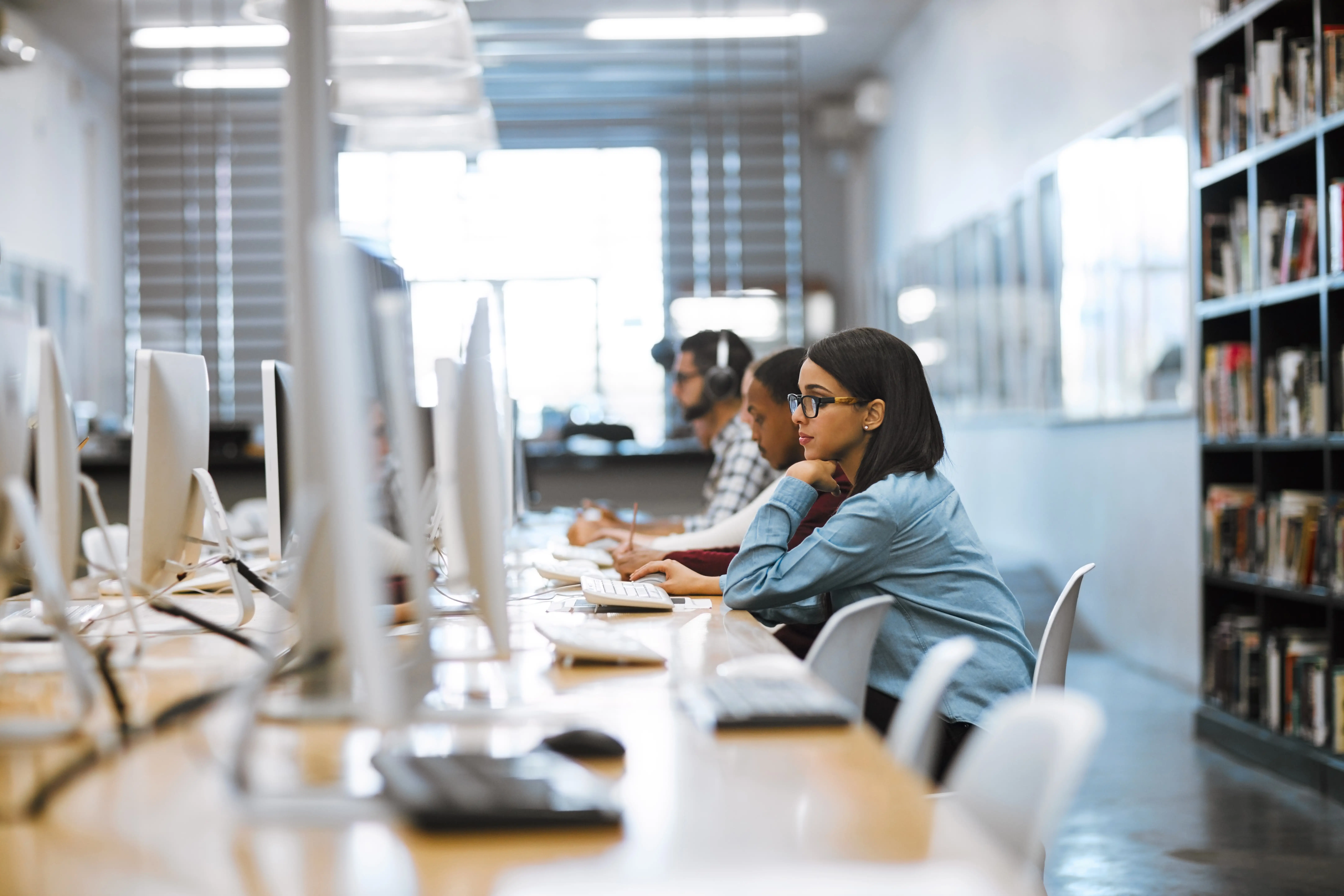 students sitting in a library staring at computer screens
