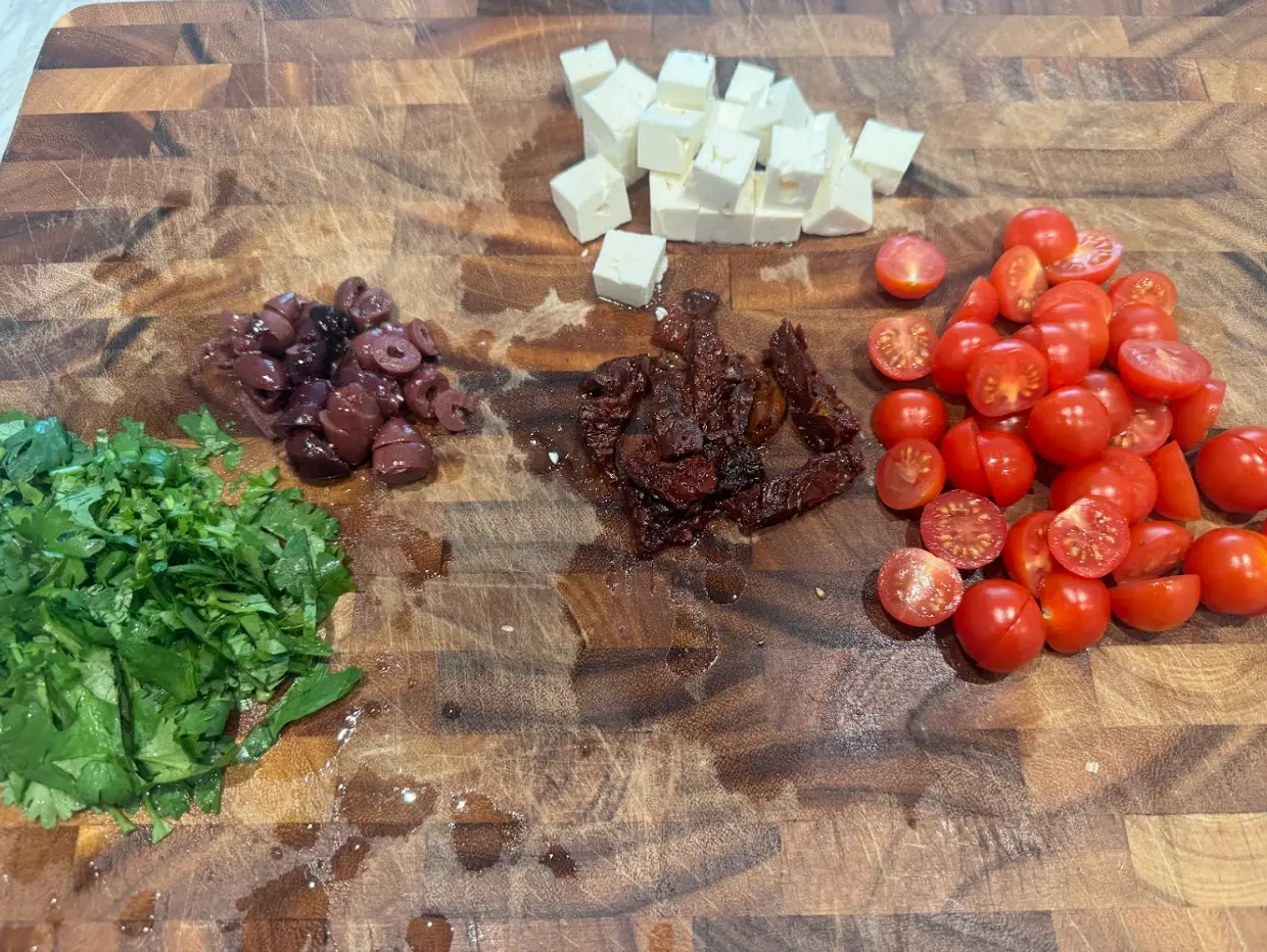 Chopped vegetables, mixings, and cheese for Ina Garten's summery pasta salad recipe.