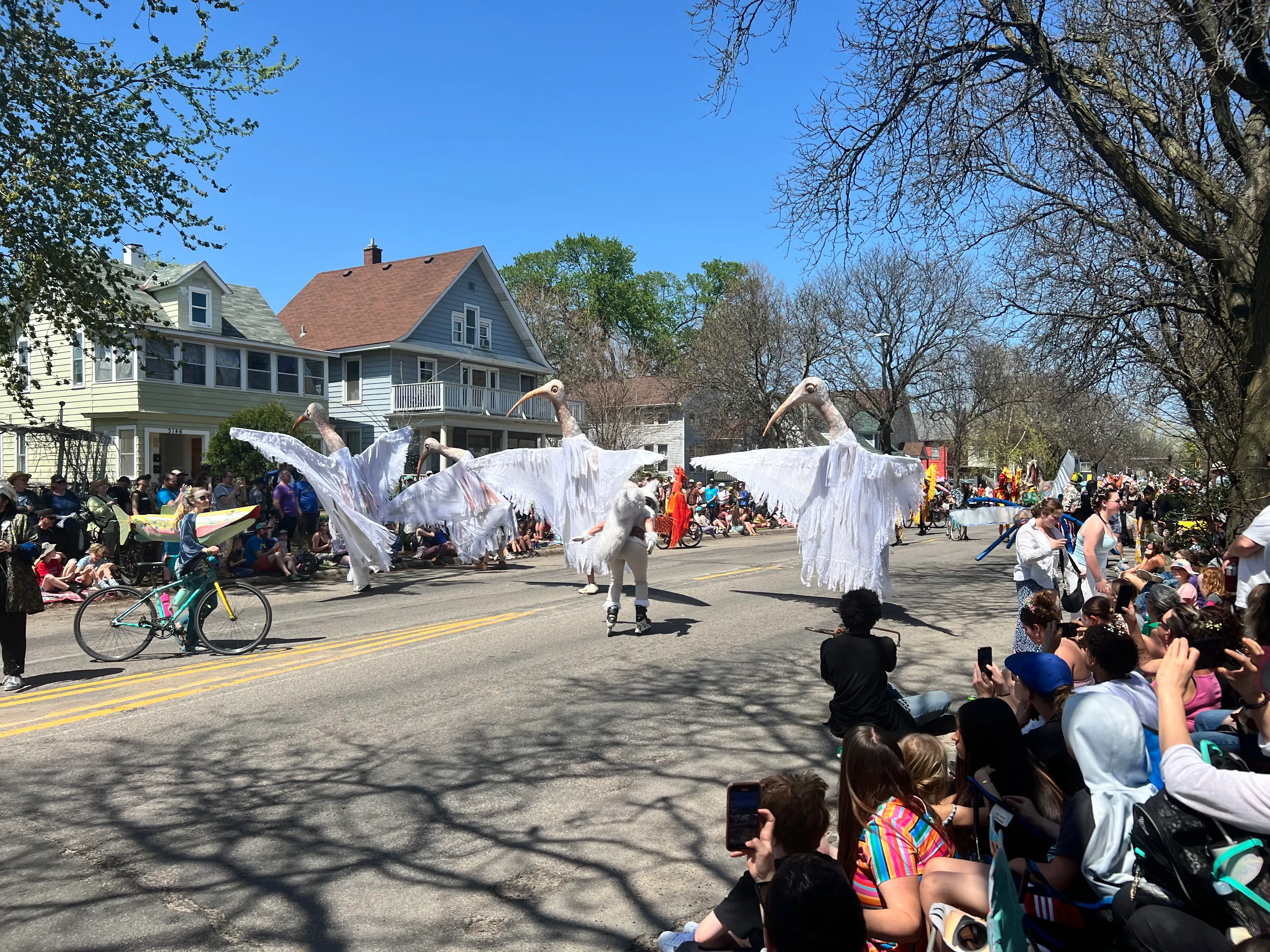People holding giant bird puppets in a parade.