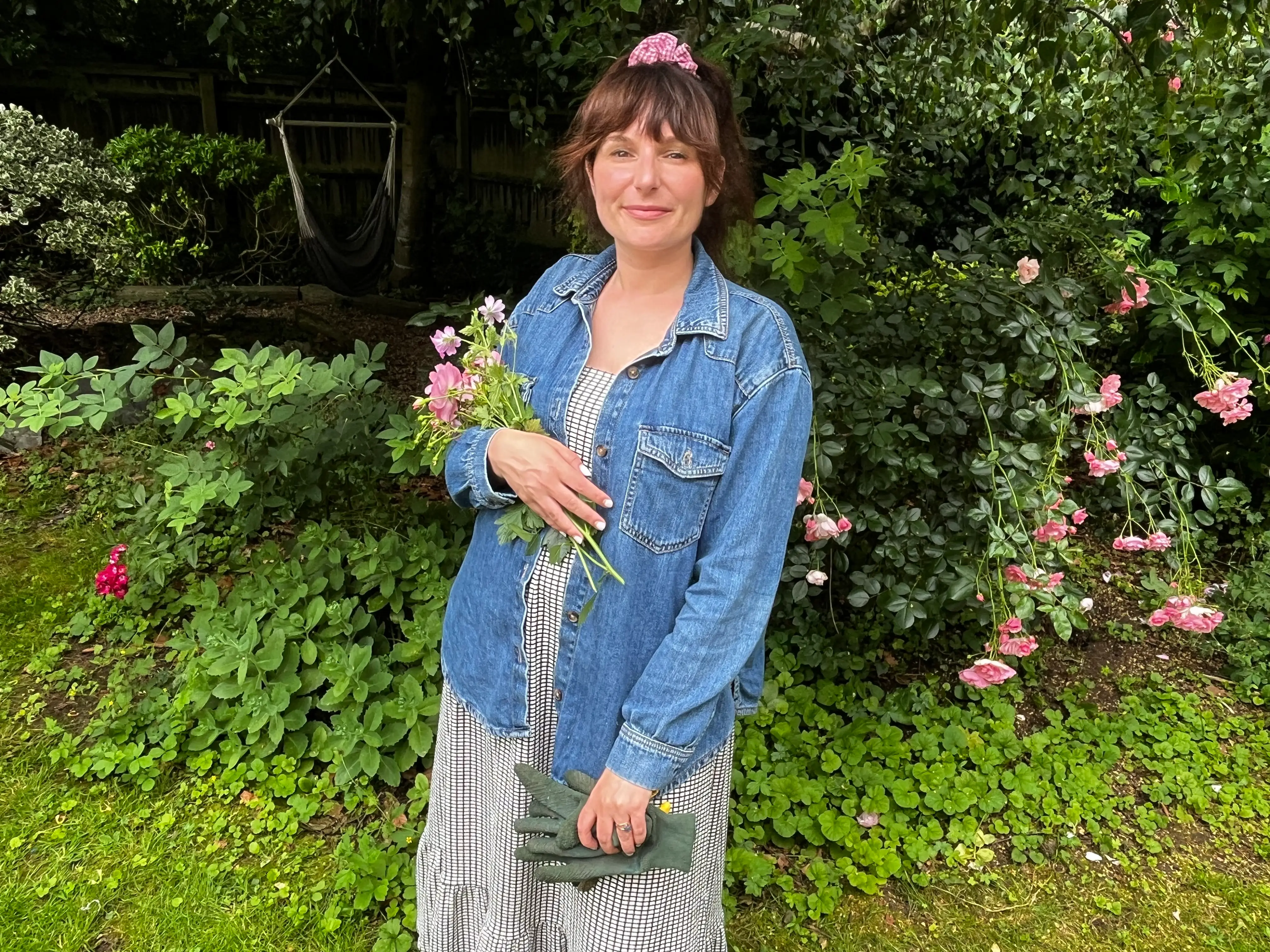 The author wearing a dress and denim jacket in a garden.