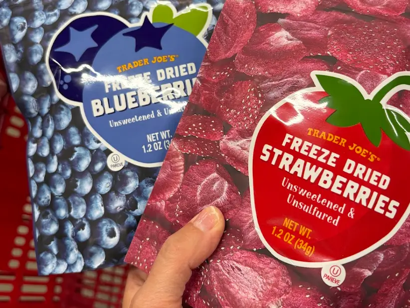 A hand holding freeze-dried blueberries and strawberries.