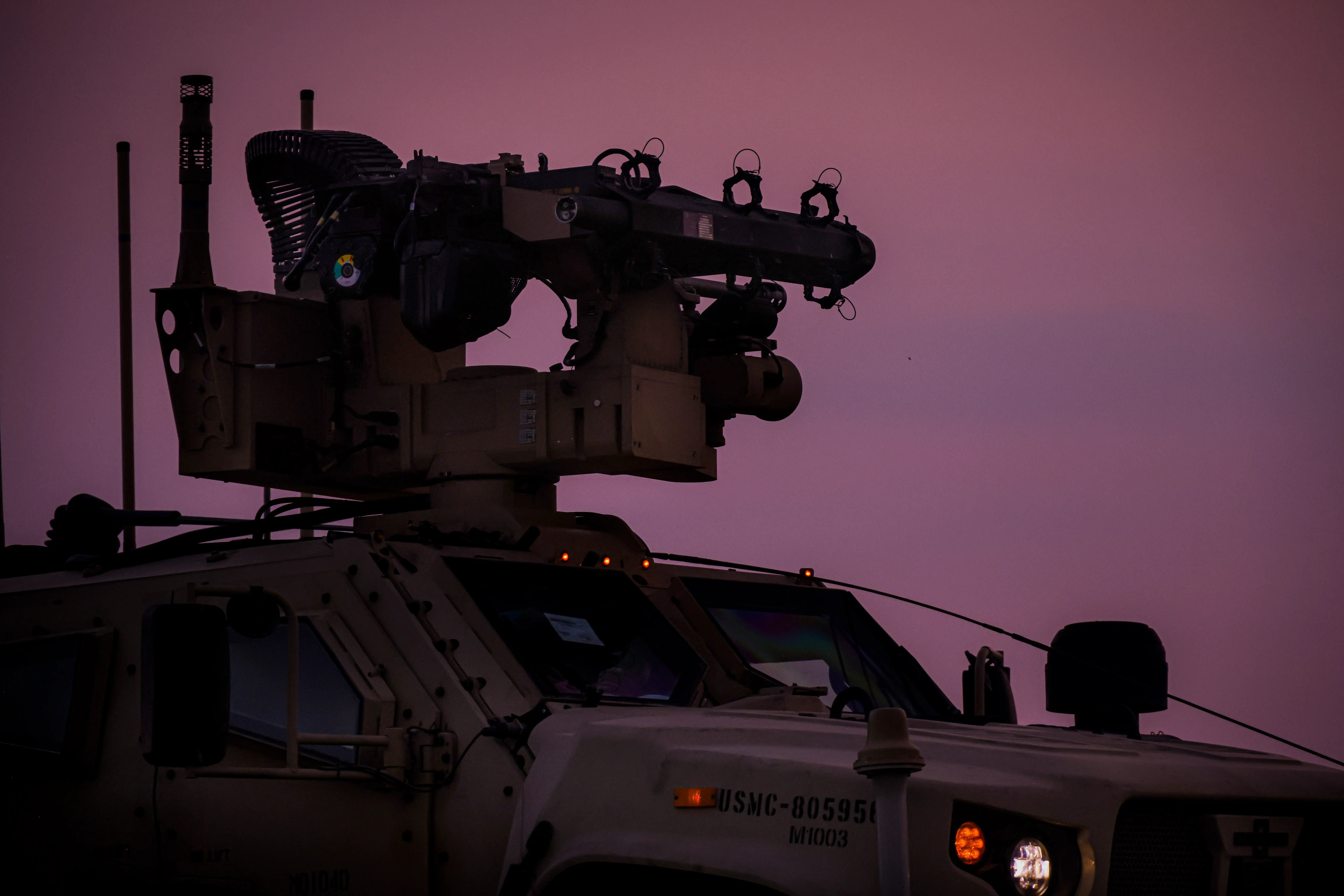 An air defense system sits on a vehicle with a sunset in the background.