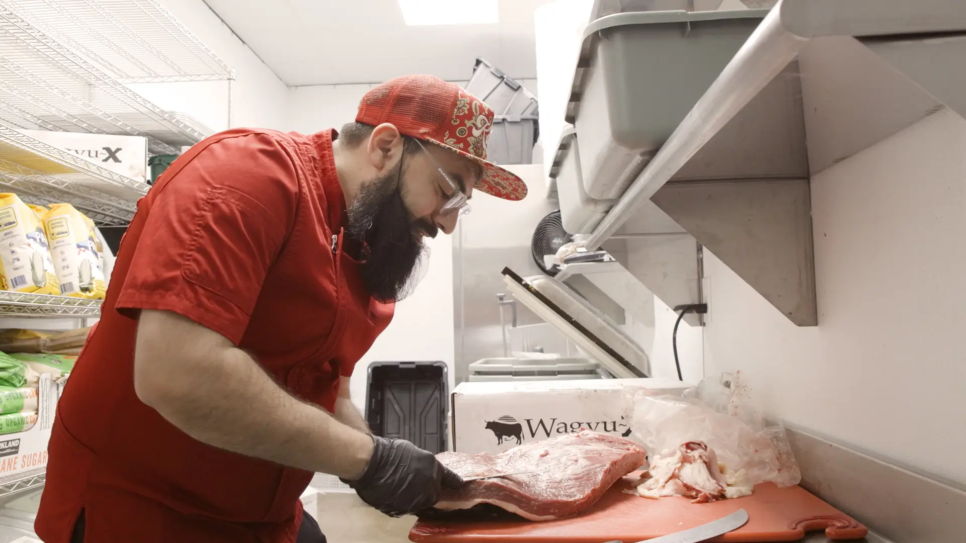 Abdul-Kafi carving a slab of meat in Kafi BBQ's kitchen.