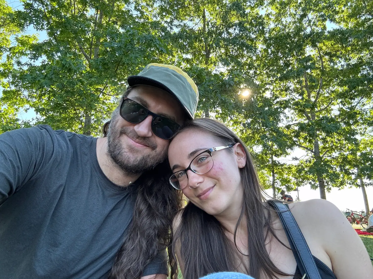 The writer and her partner sitting outside, under the shade of trees.
