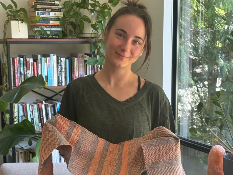 The writer holding a scarf she knitted in her house.