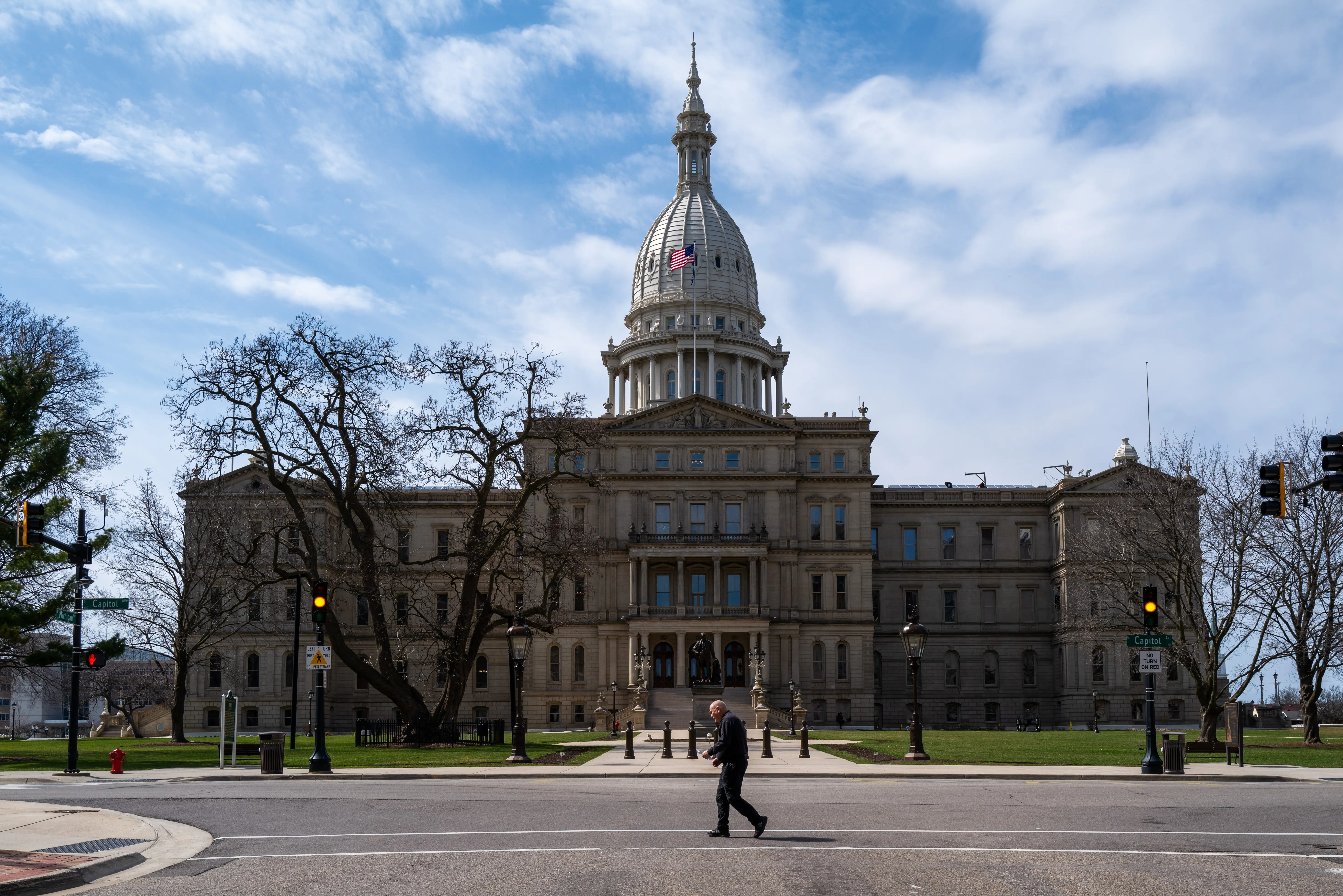 A man crosses the street in front of the state capital building in downtown Lansing on April 01, 2024 in Lansing, Michigan.