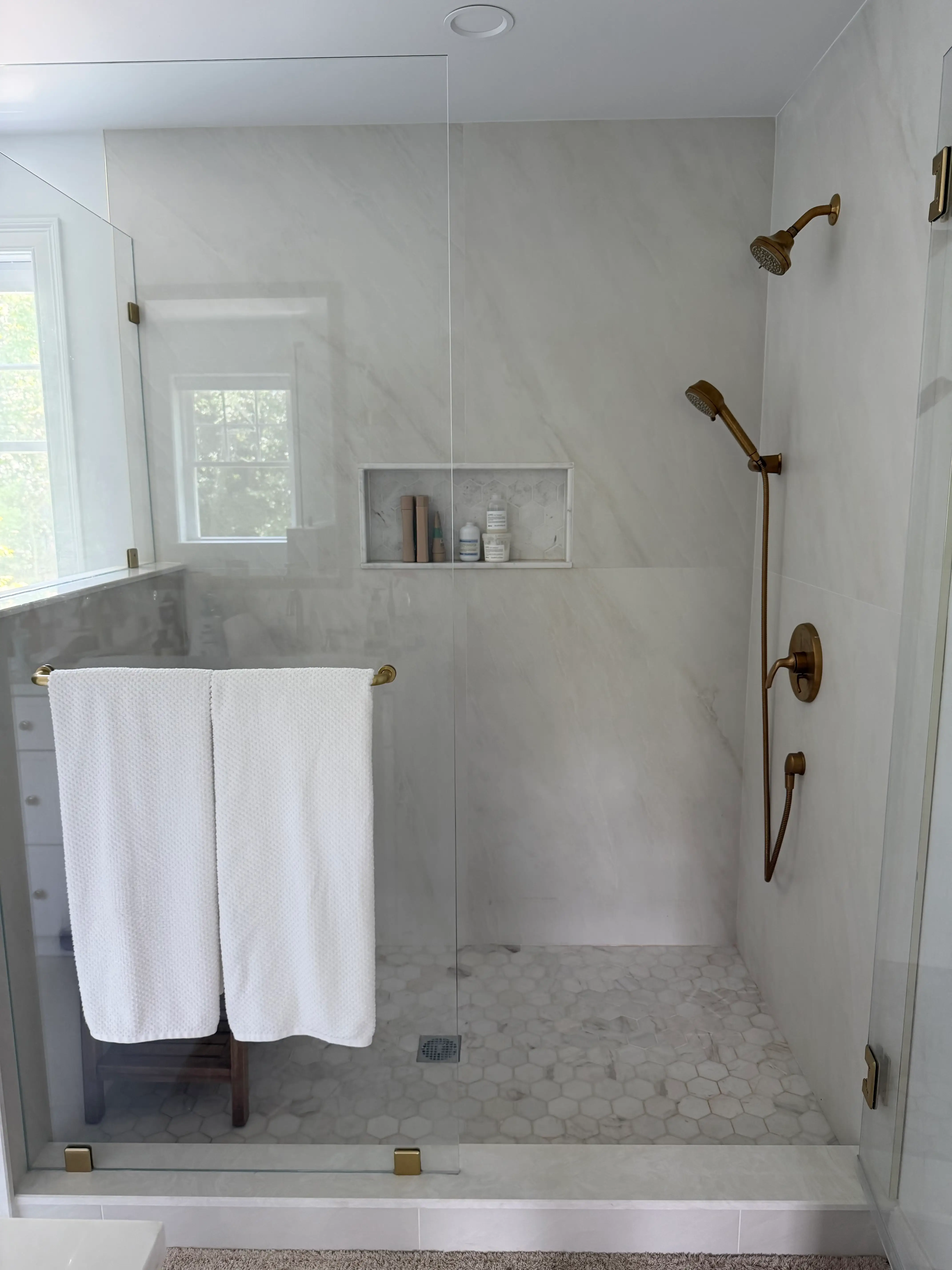 A large, walk-in shower with built-in shelving.
