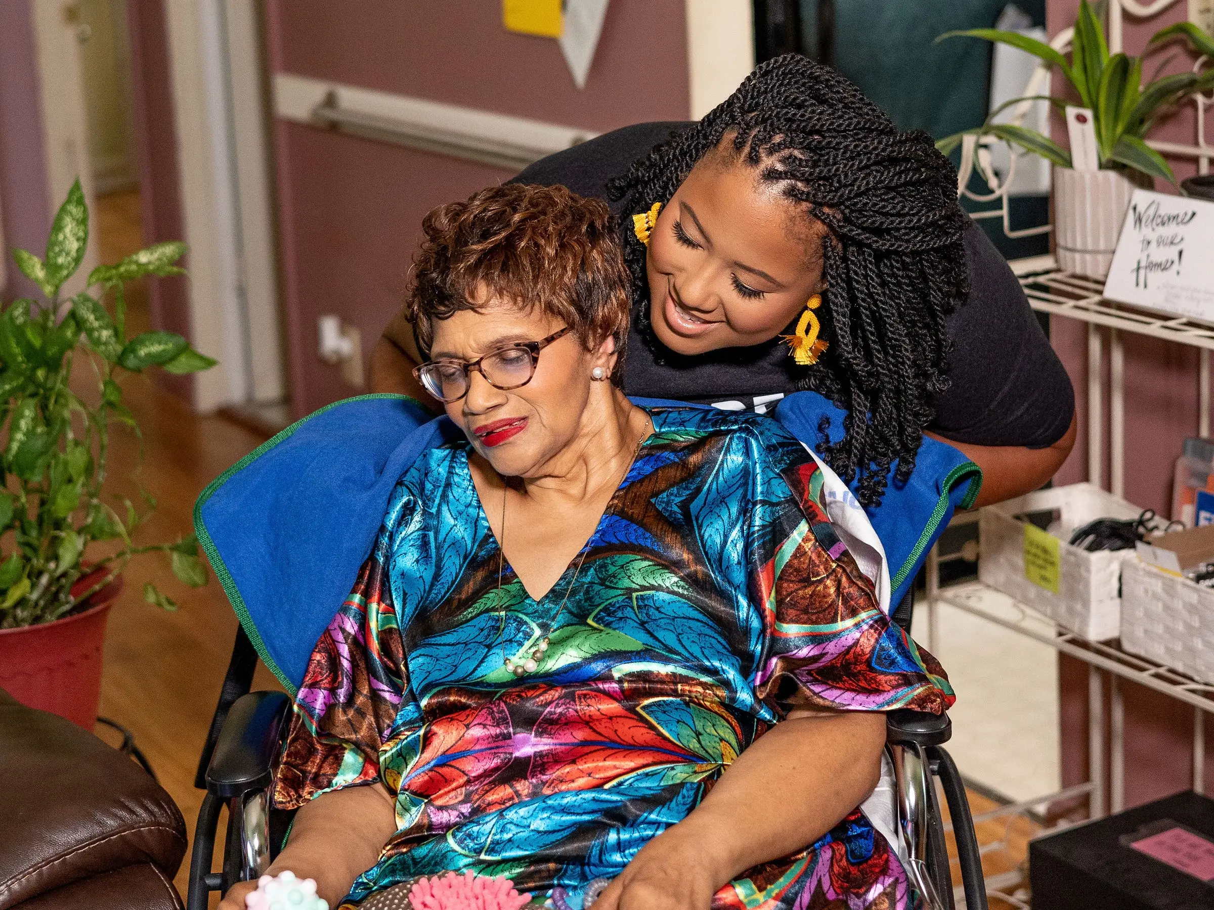 A woman pushing an older adult in a wheelchair.