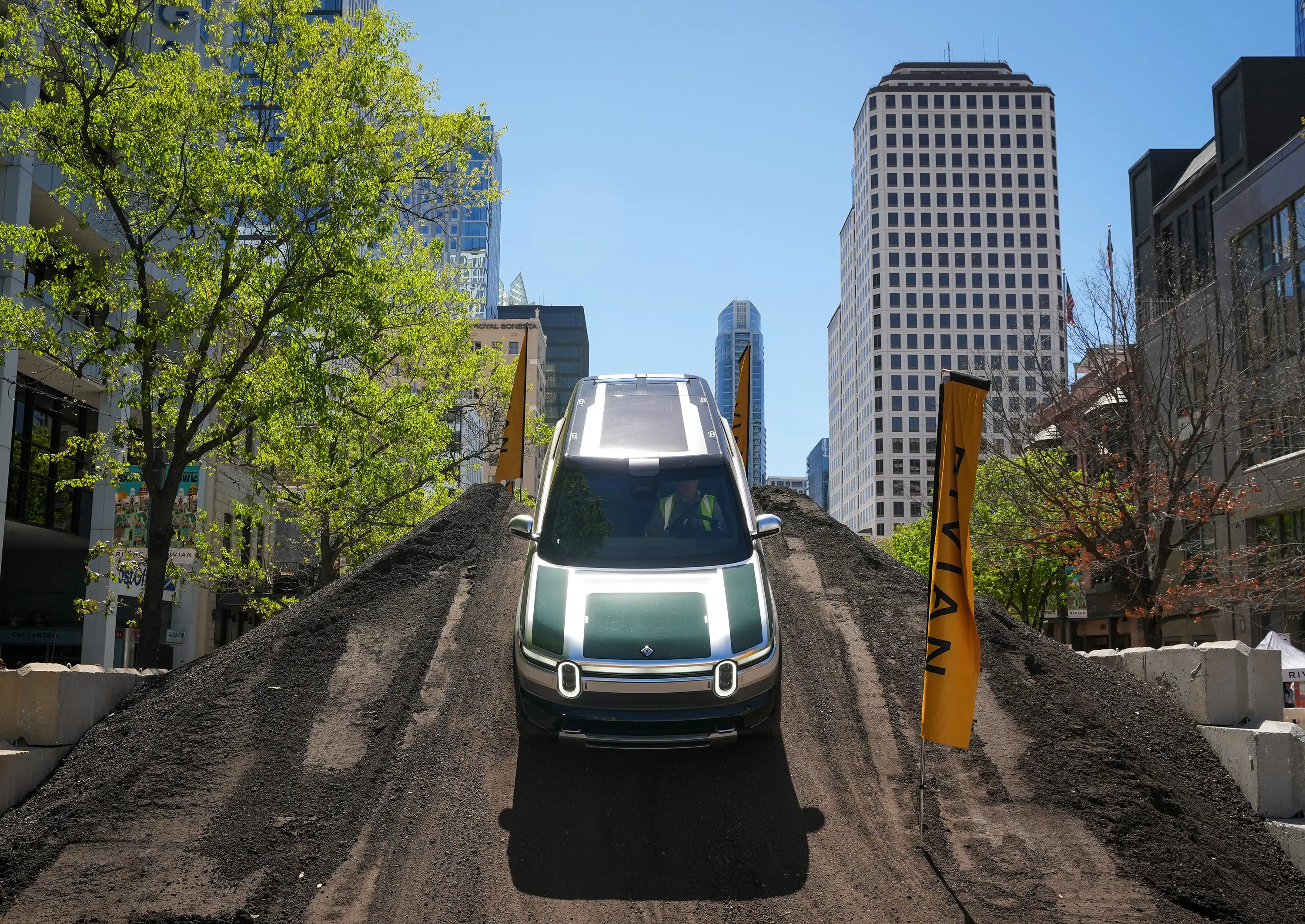 A Rivian R2 prototype drives down a dirt hill.