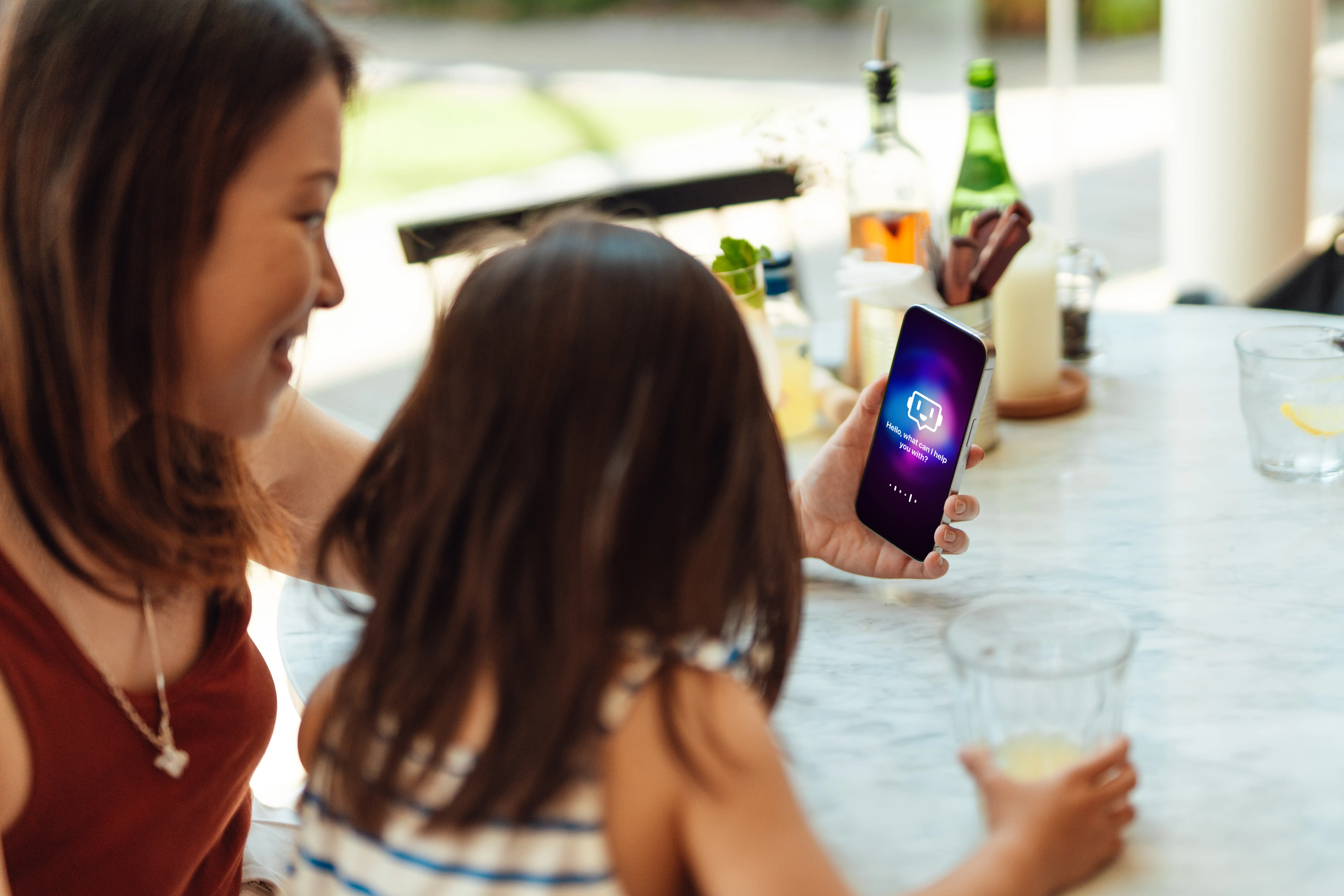 A woman holds up a cell phone in front of a young girl.