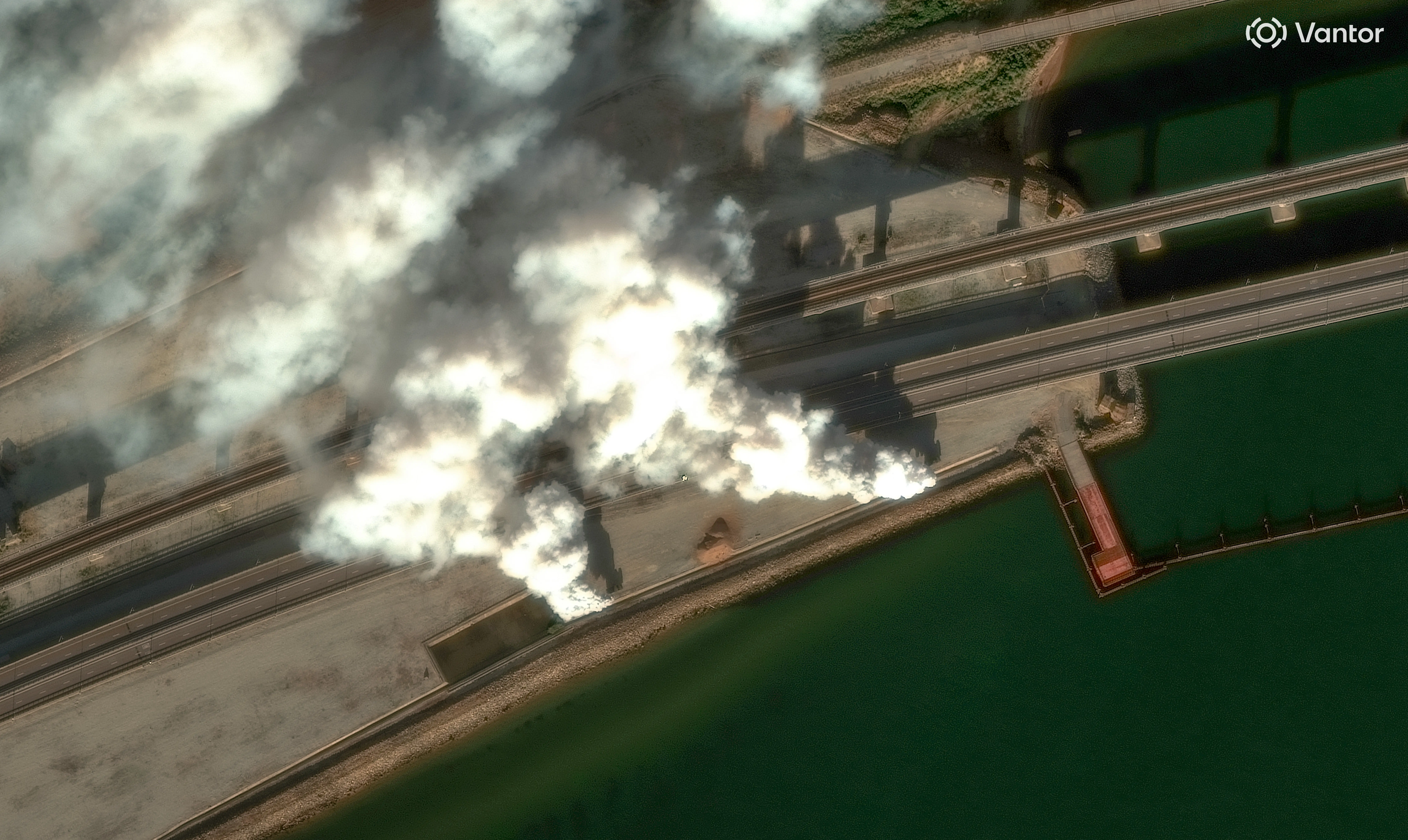 Two white and grey smoke stacks rise from a bridge.