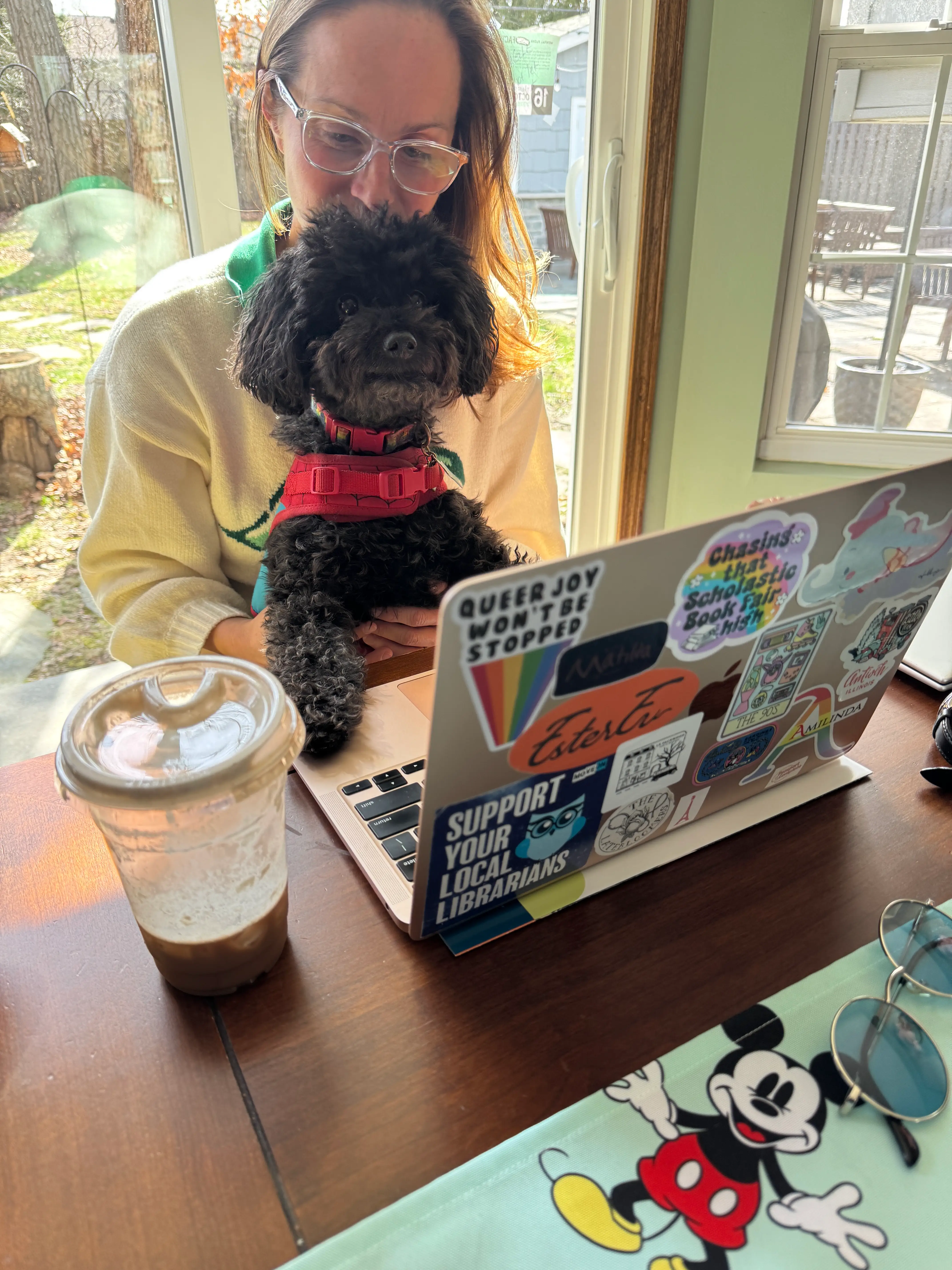 The author sits at a laptop with a dog on her lap and coffee by her side while applying for a job.