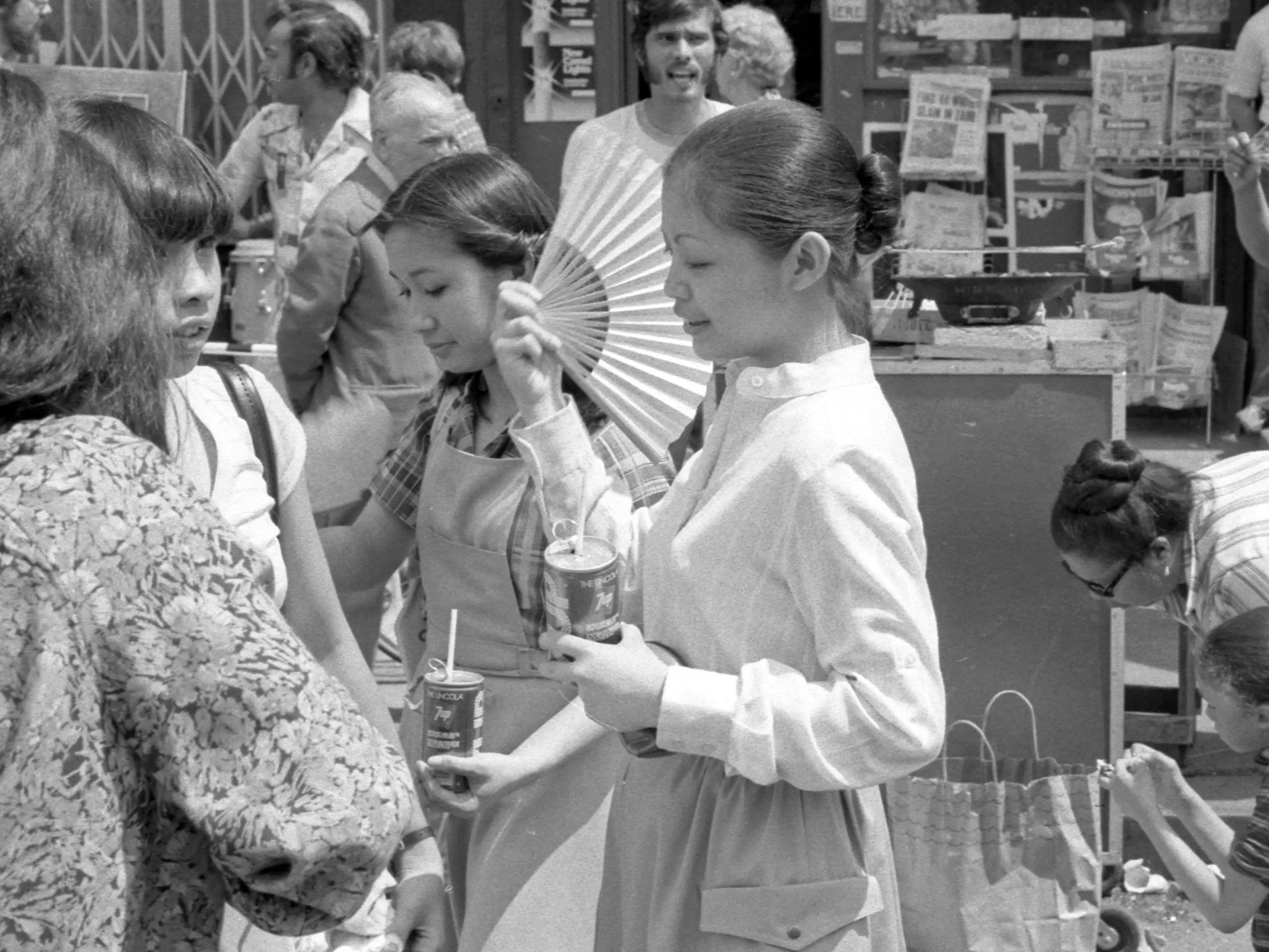 Woman holding a drink and a handheld fan