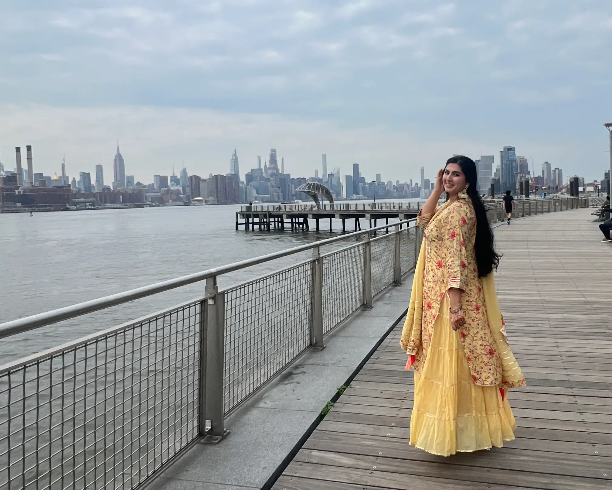 Woman posing near bridge with view of skyline in background