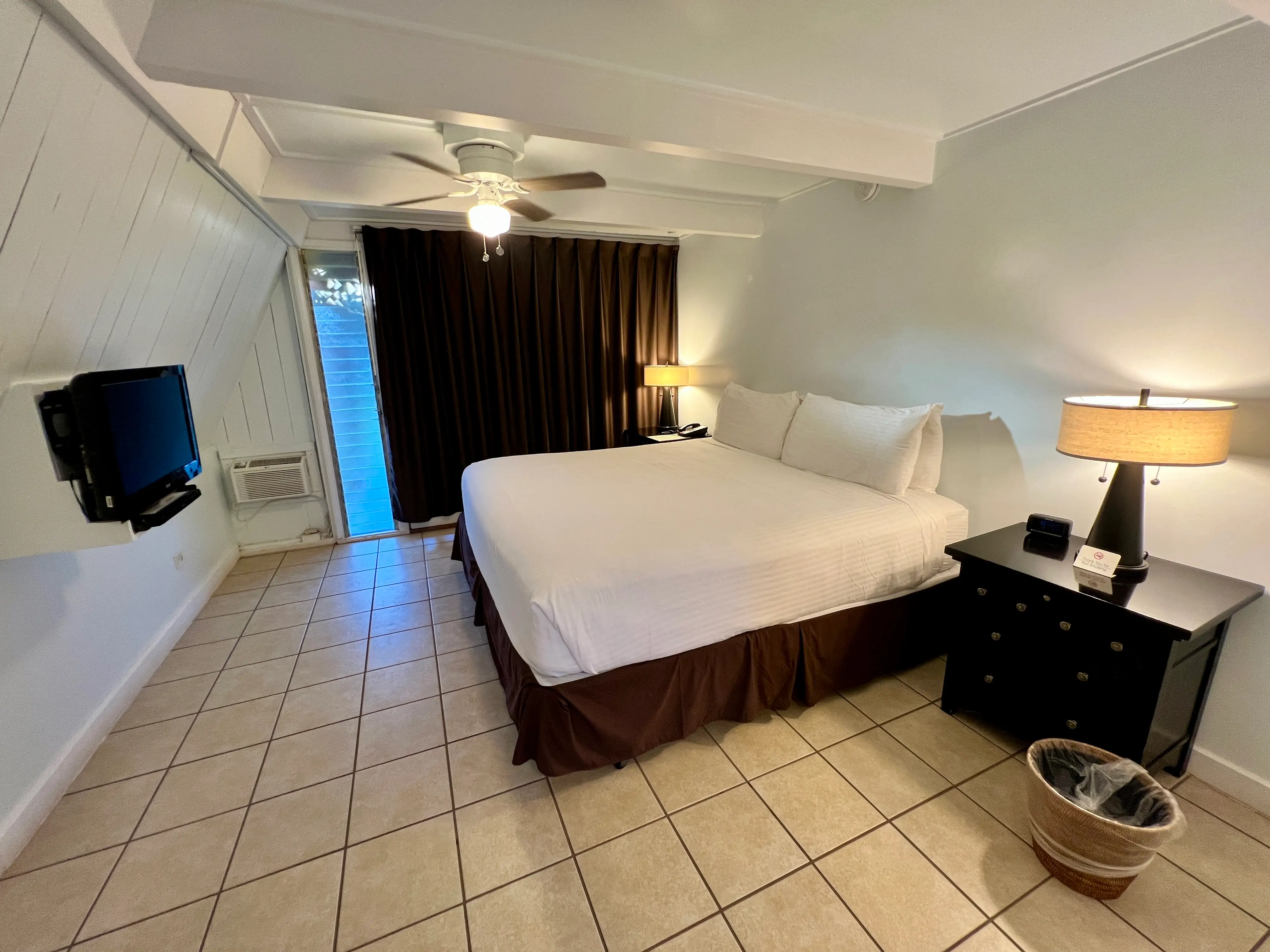 Simple room with white walls, brown curtains blocking door, small TV, one dresser