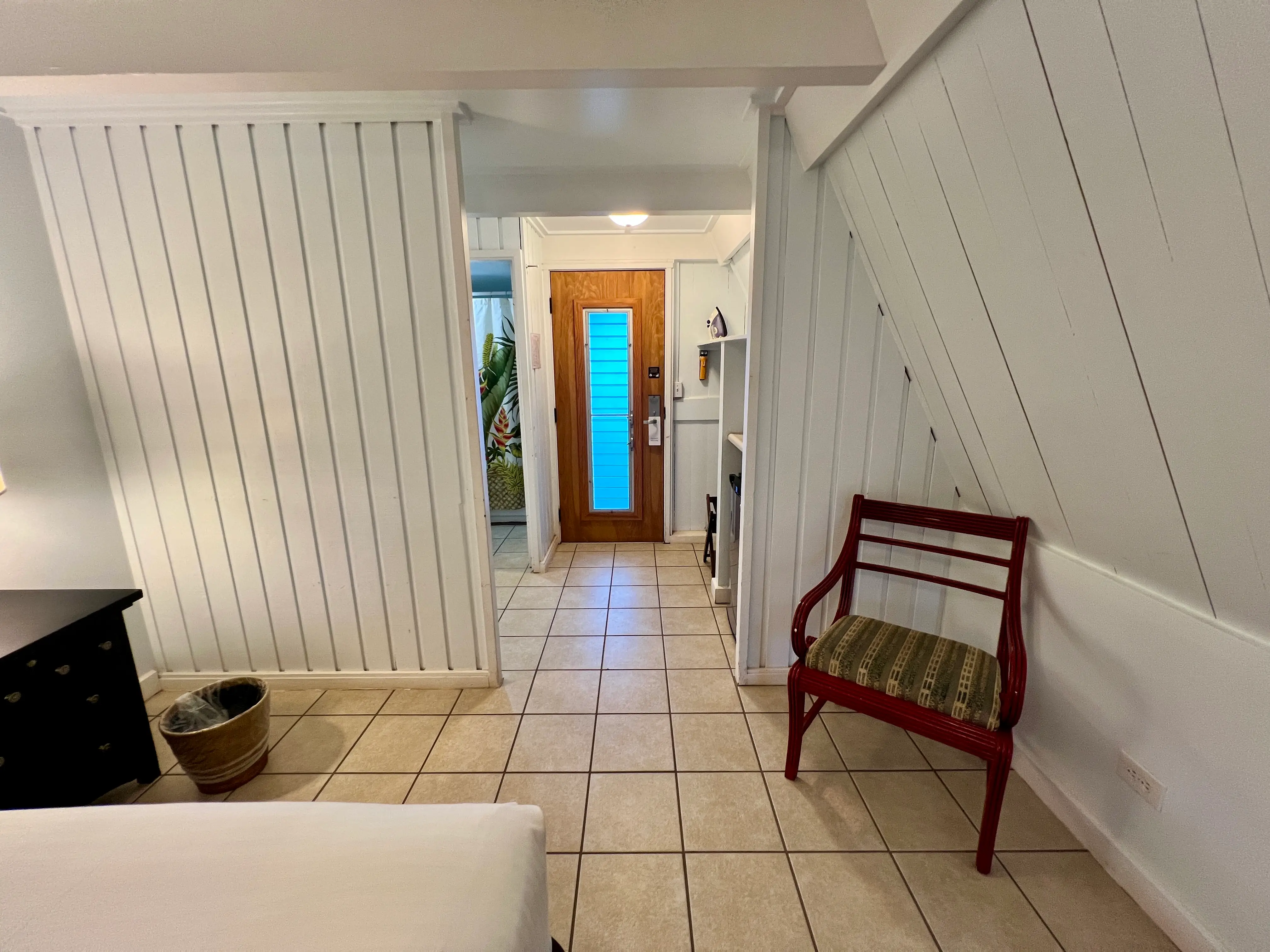 Slanted white walls above tiled floor with view of wood and glass door