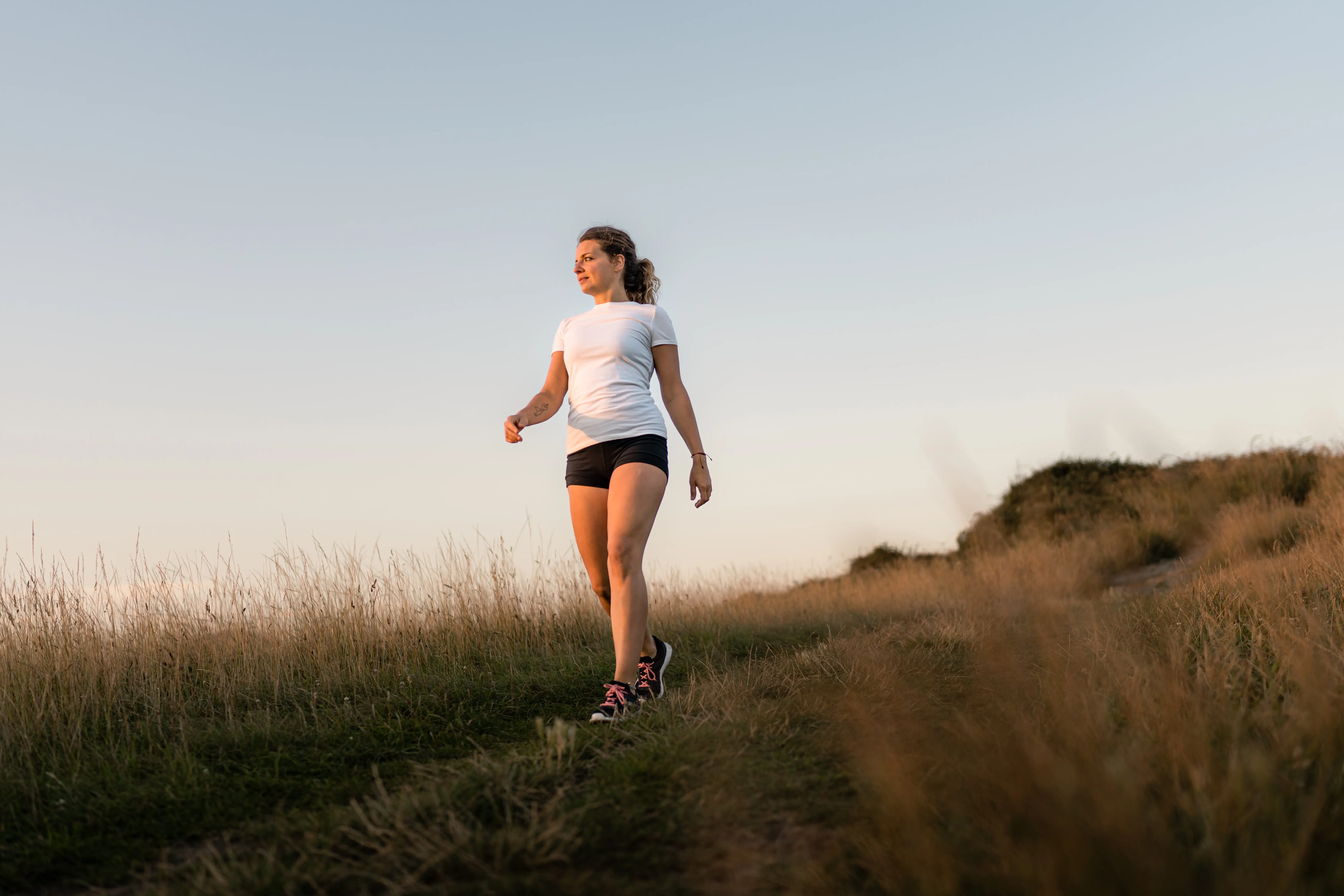A stock image of a woman walking through long grass.