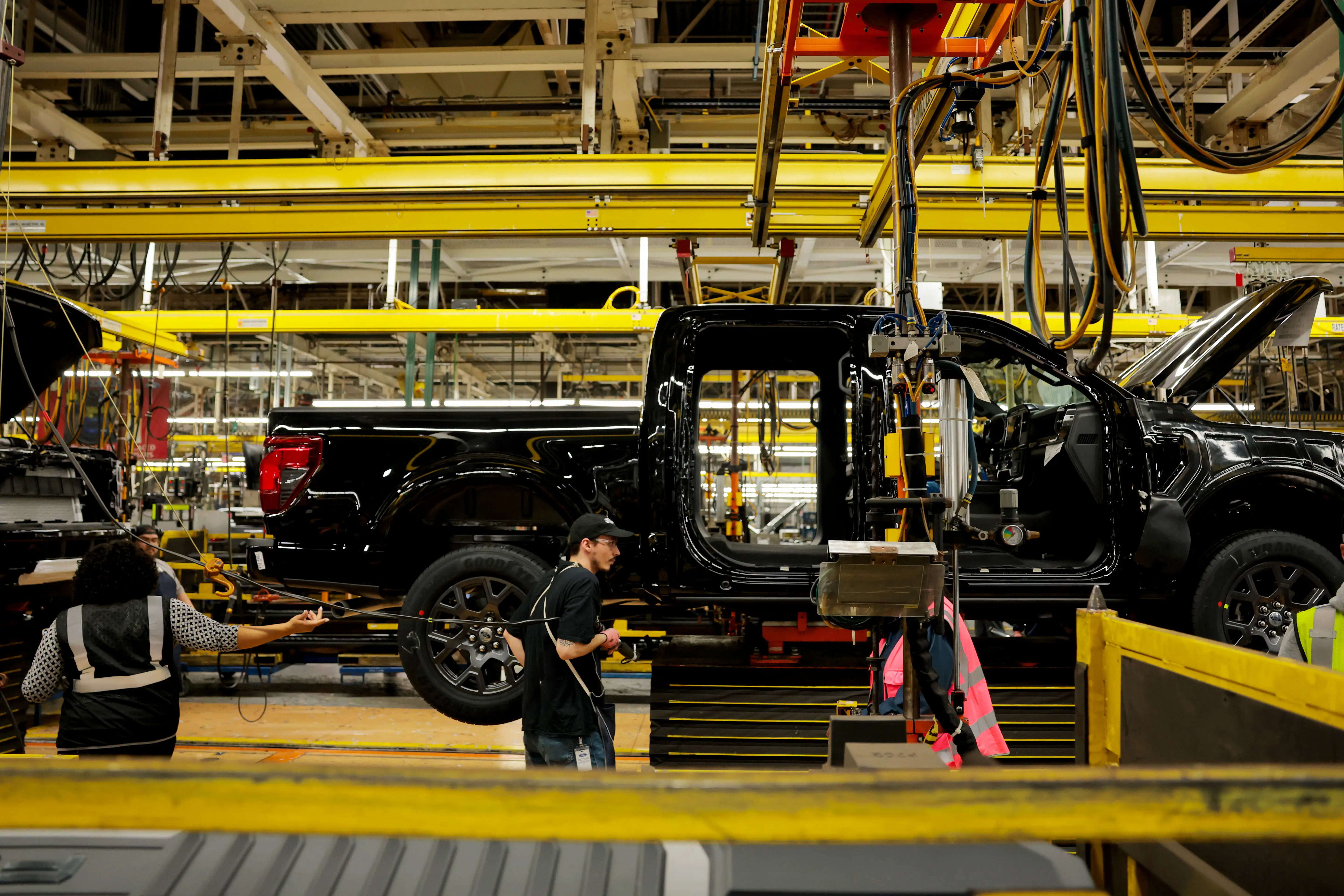 Workers assemble a black Ford F-150 on the assembly line.
