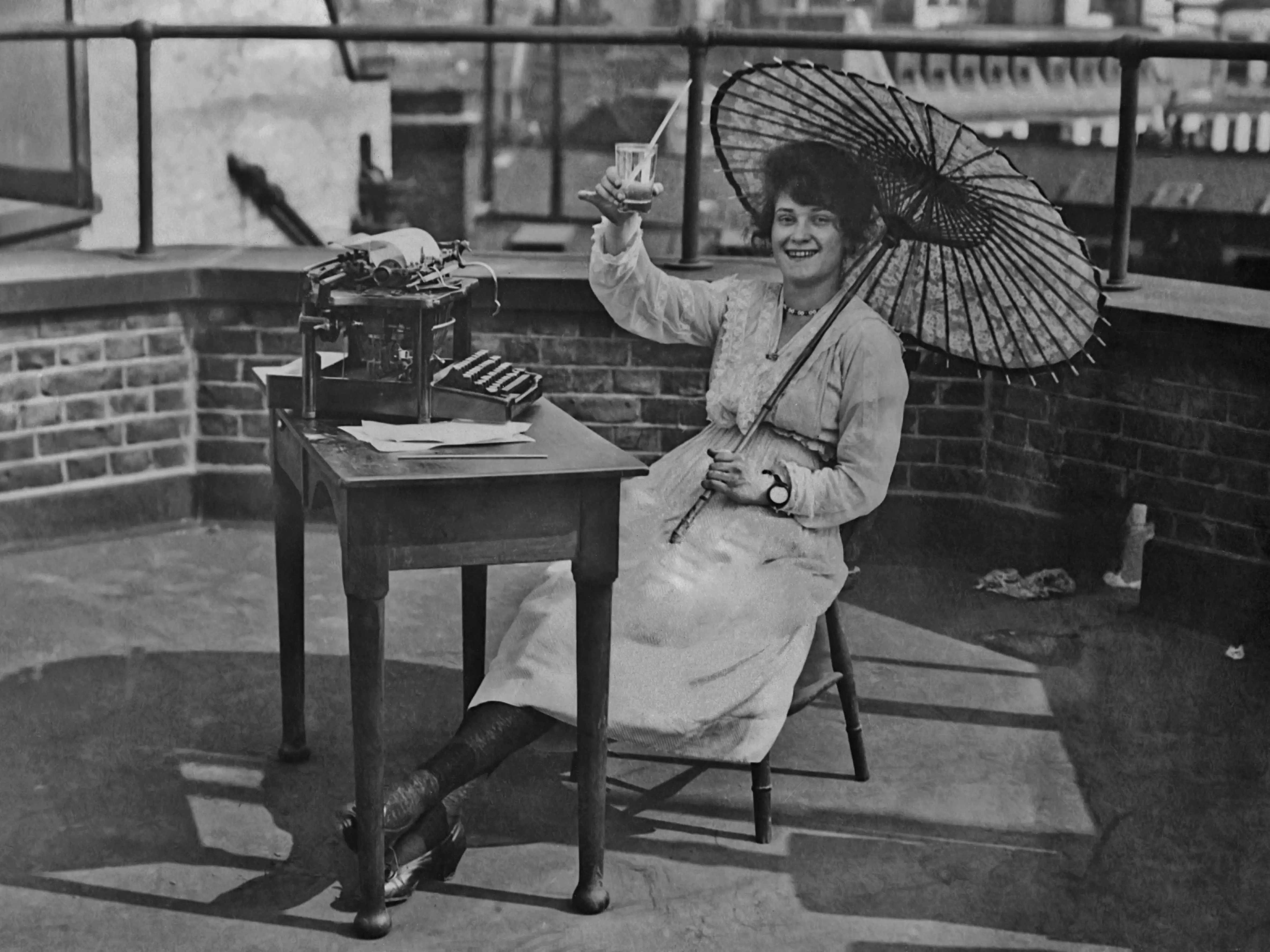 A woman holds up a drink under an umbrella