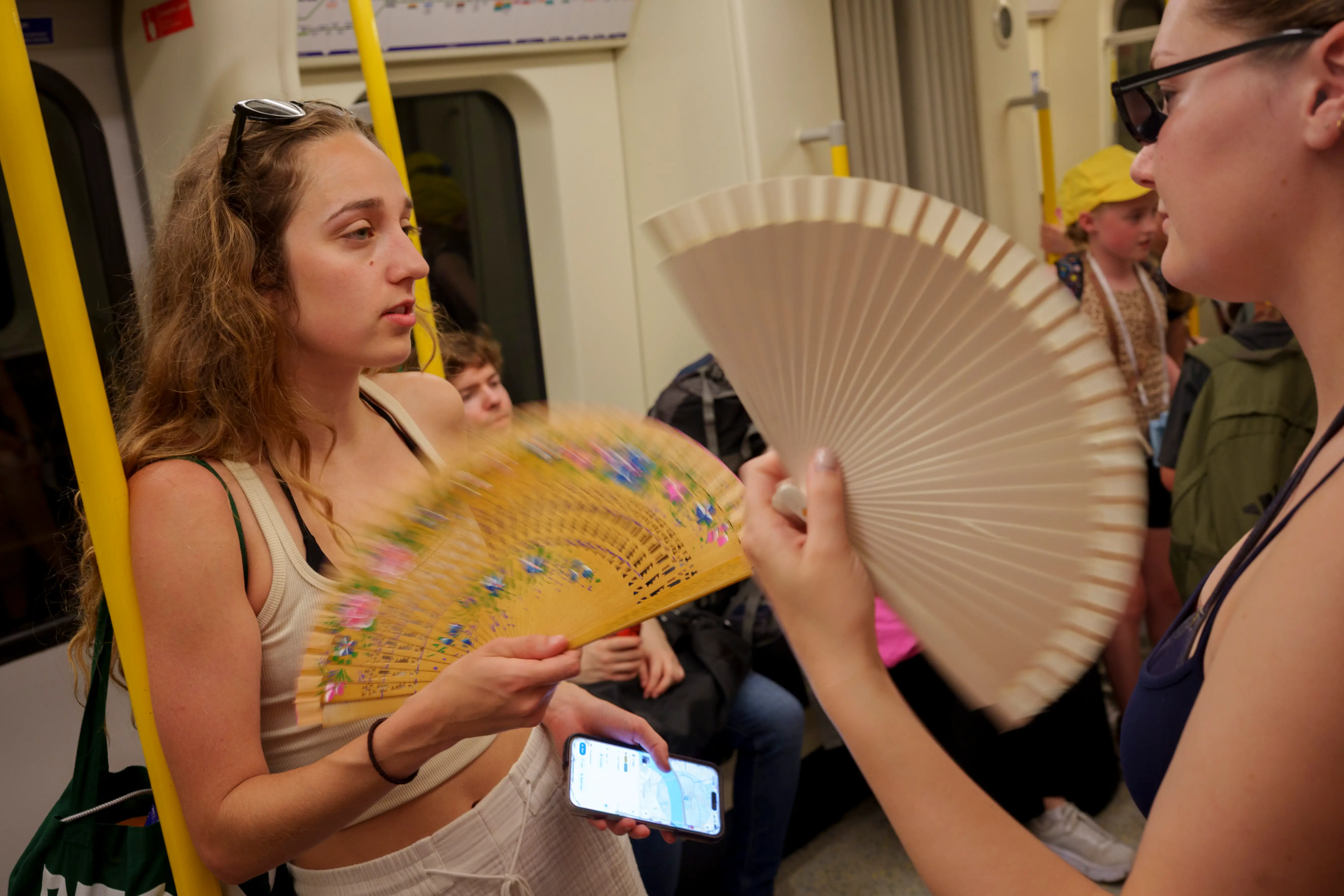 People hold fans on the tube in London.