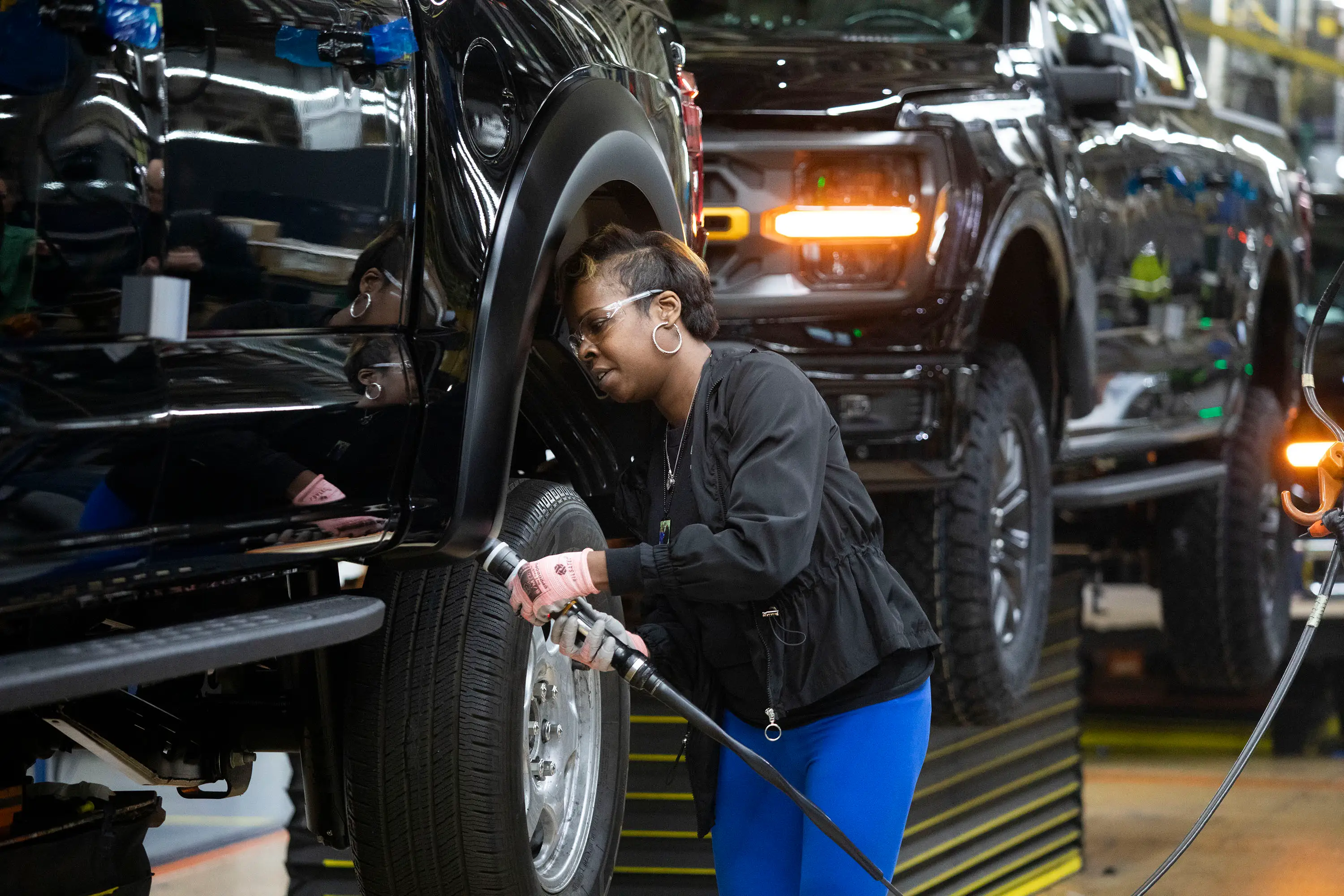 A Ford assembly worker uses a hose-like instrument on the Ford F-150 factory line.