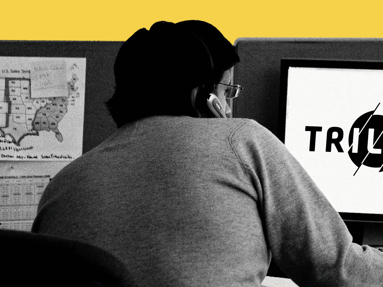 A man working at a desk with a Triller logo that is slowly disappearing