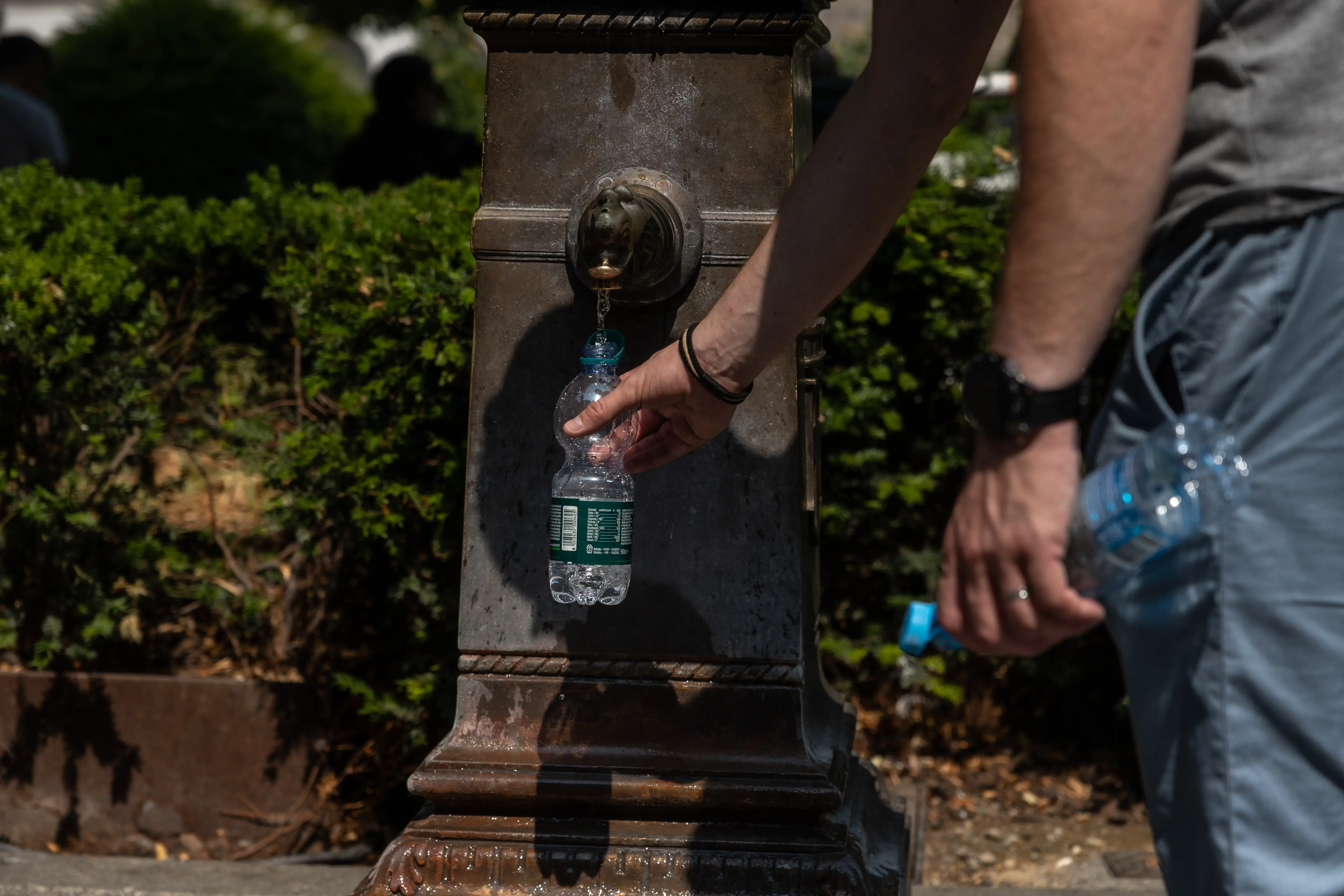 A man fills a plastic water bottle in Piazza della Scala in Milan, Italy.