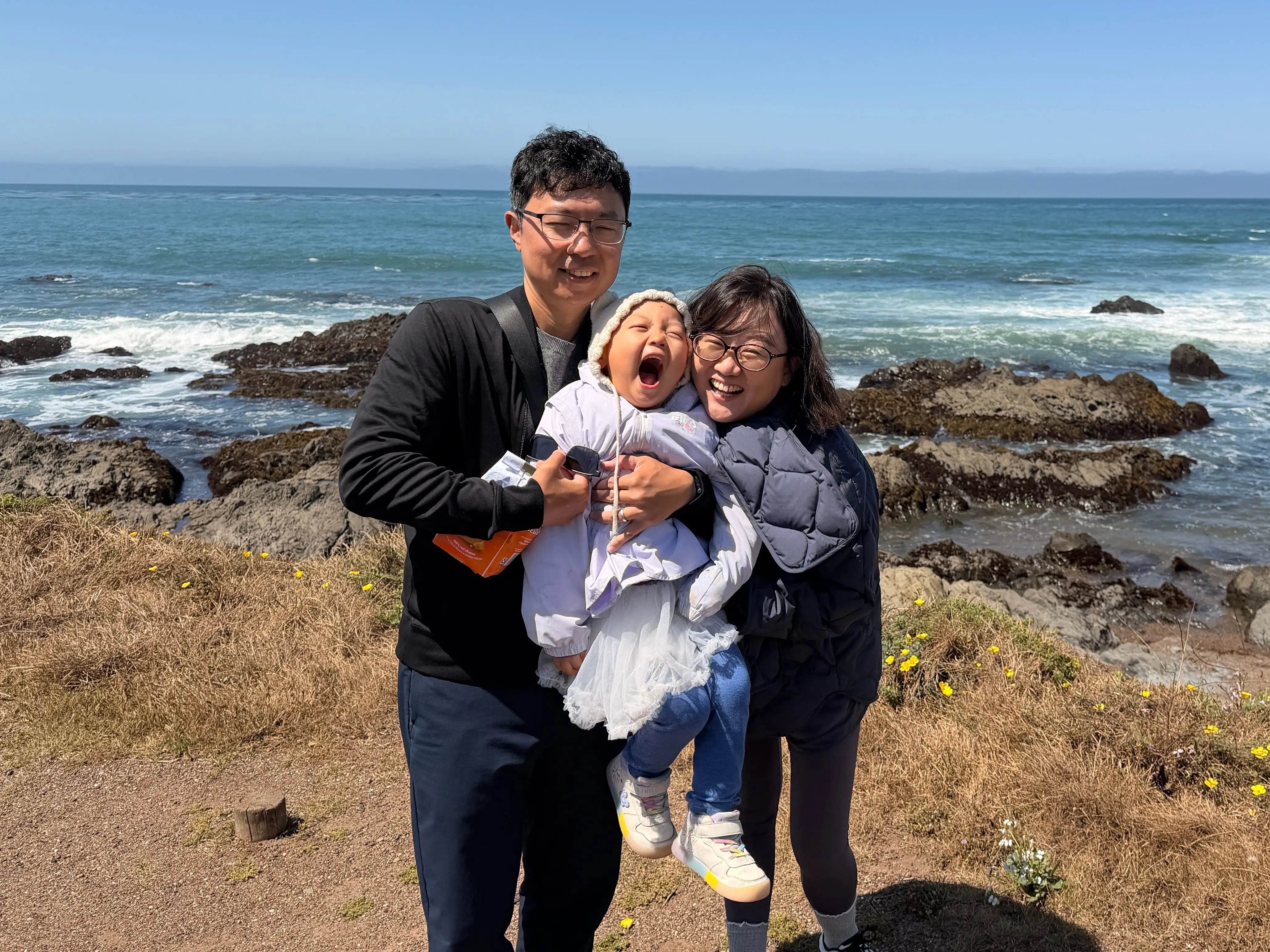 Family of three by the sea in California.