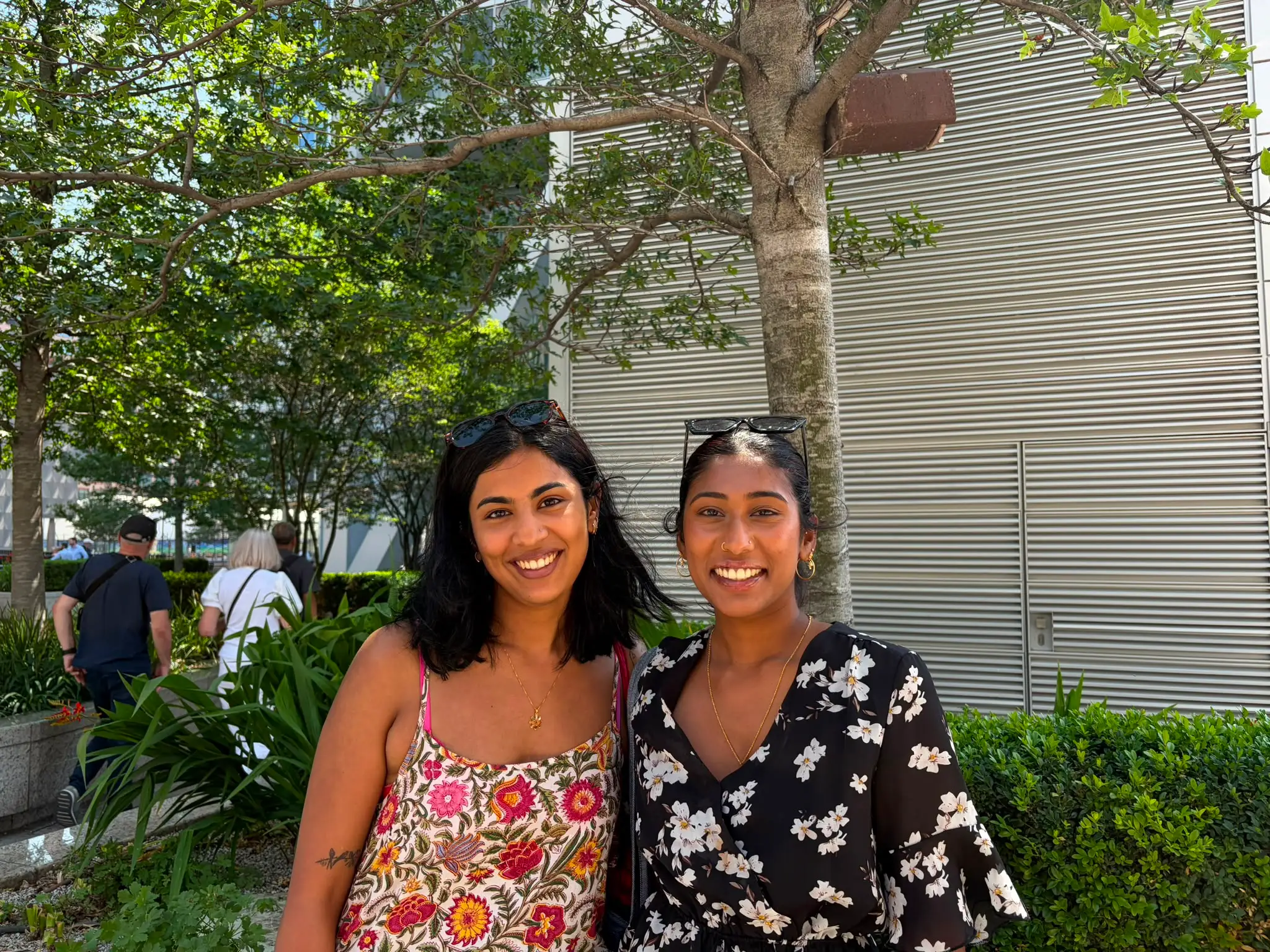 two young women stand in front of a tree