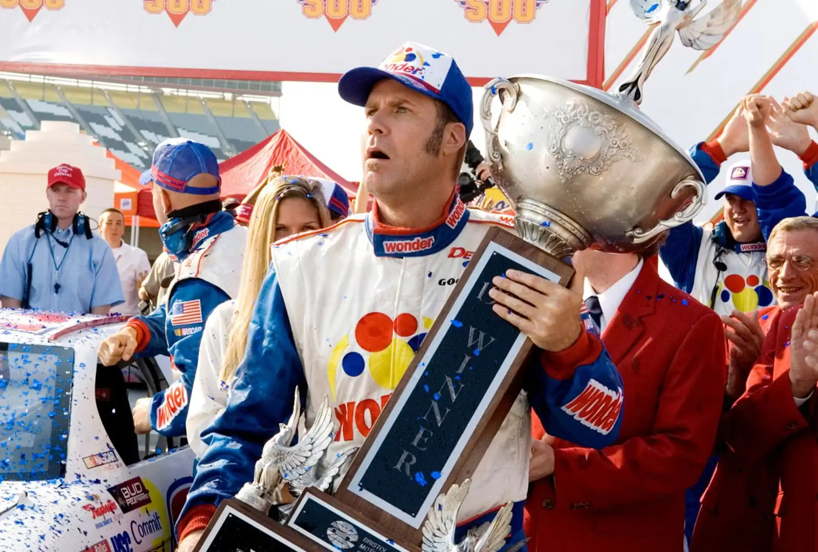 Will Ferrell holding a trophy next to a race car in Talladega Nights movie