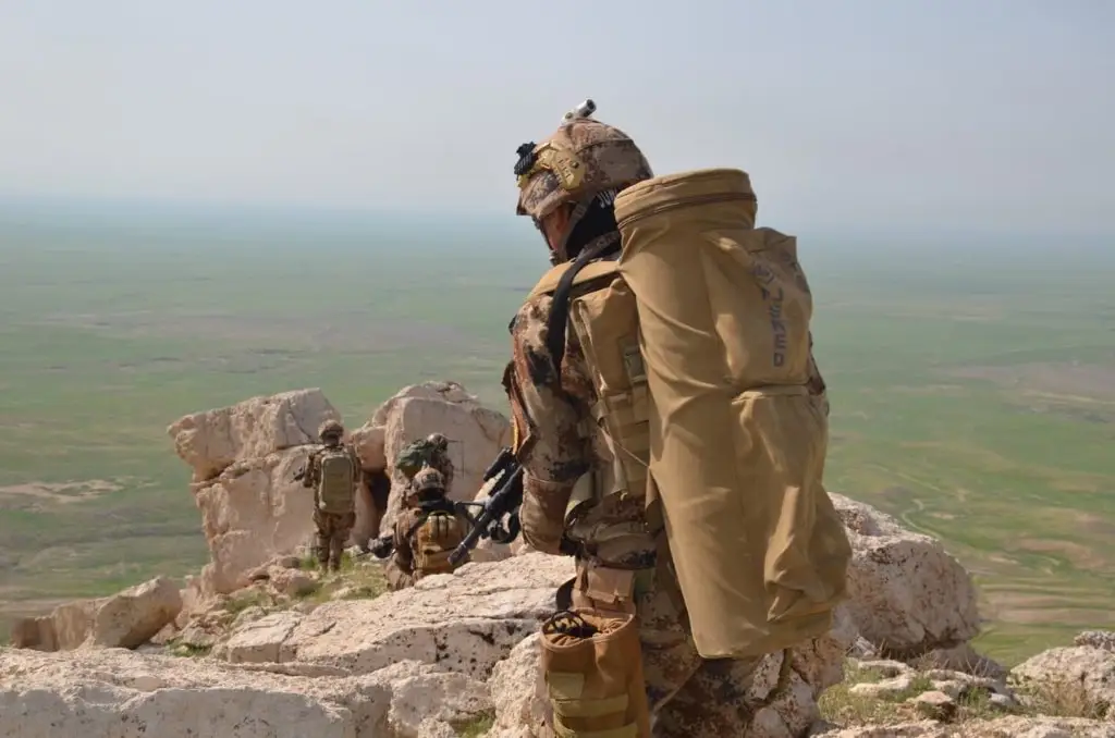 American soldiers amid high ground and rocks in Iraq.