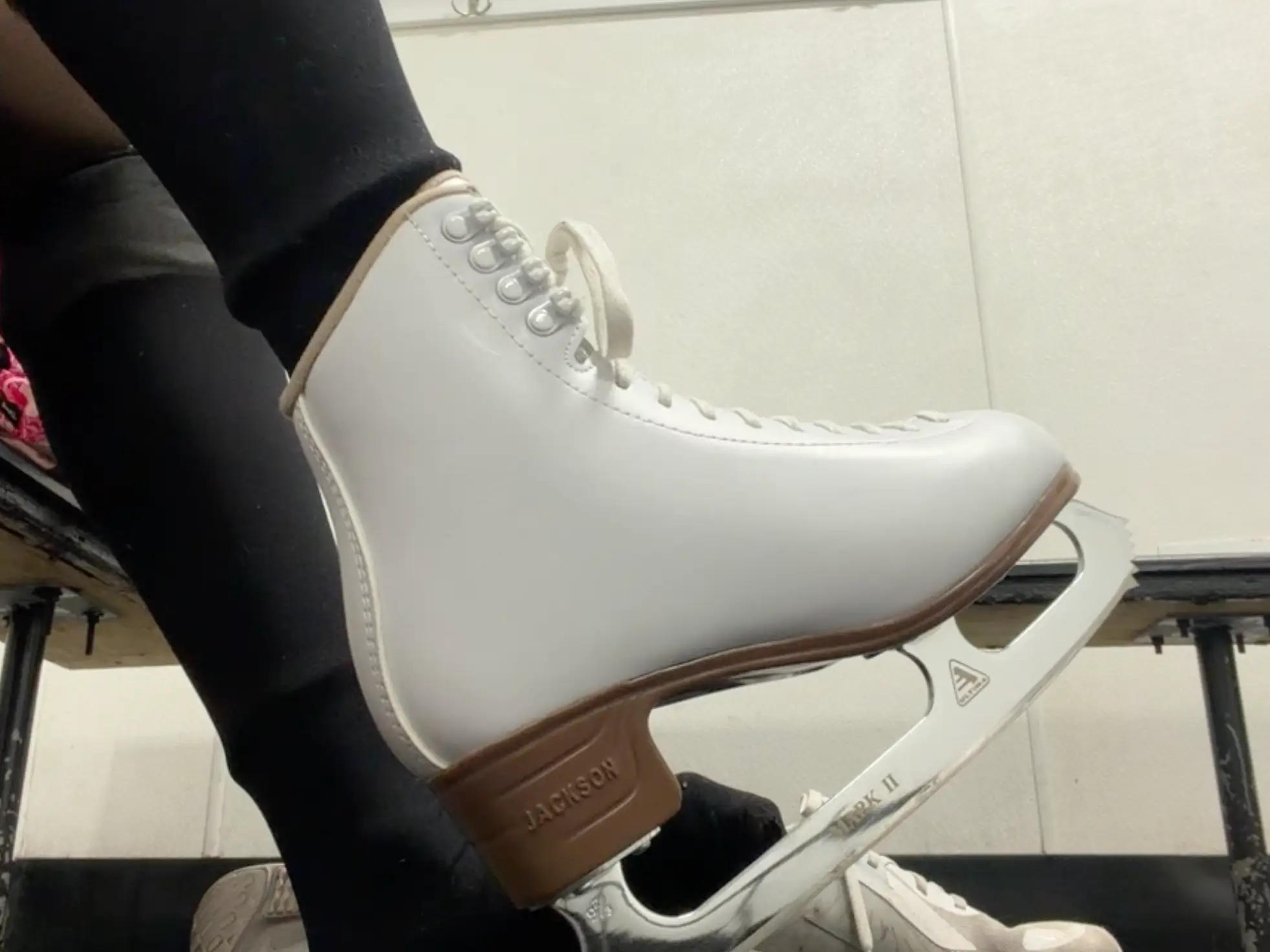 A woman lacing up her ice skates before practicing her skills at a rink.