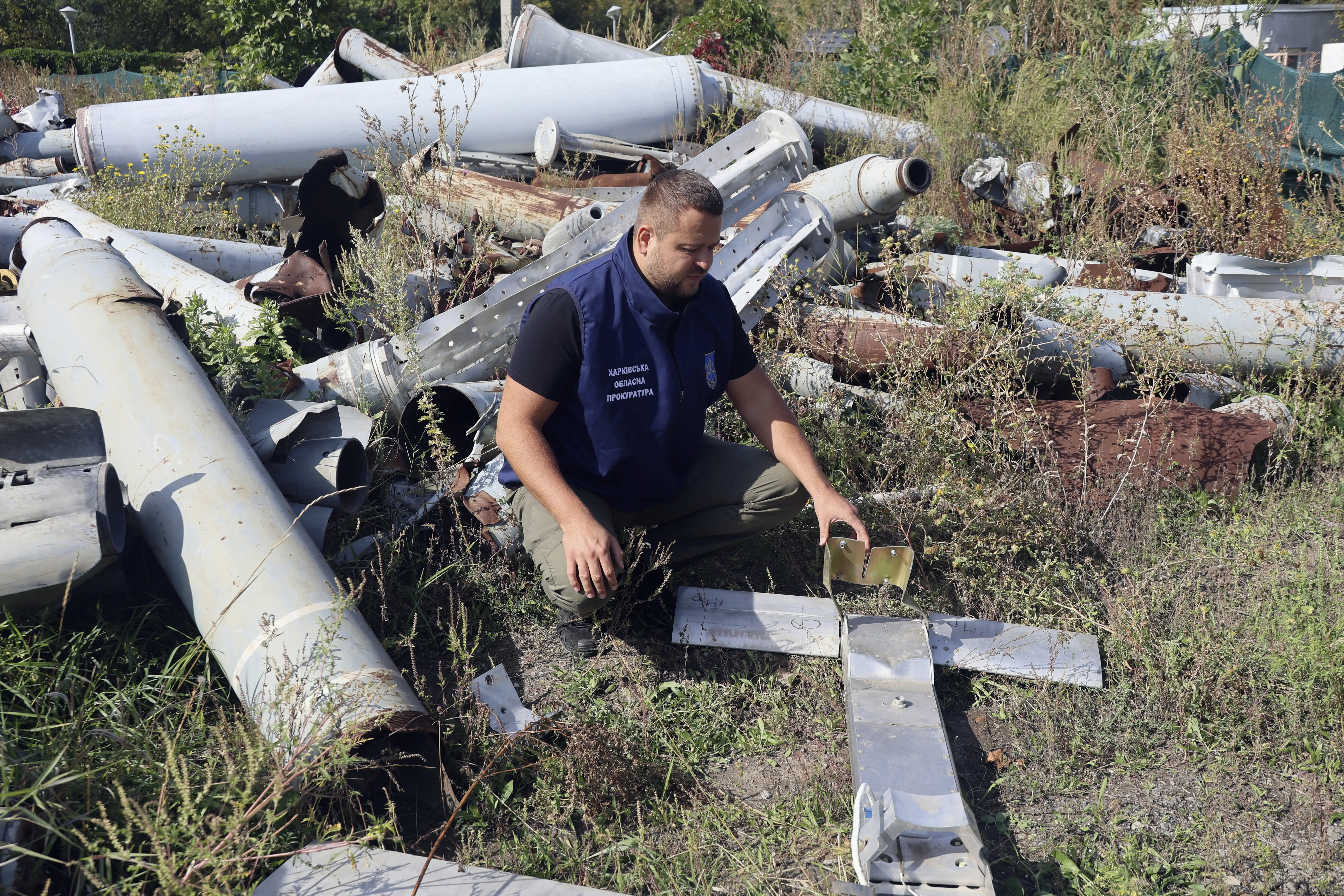 An employee of the Kharkiv Regional Prosecutor's Office of Ukraine squats by a fragment of a Russian guided aerial bomb.