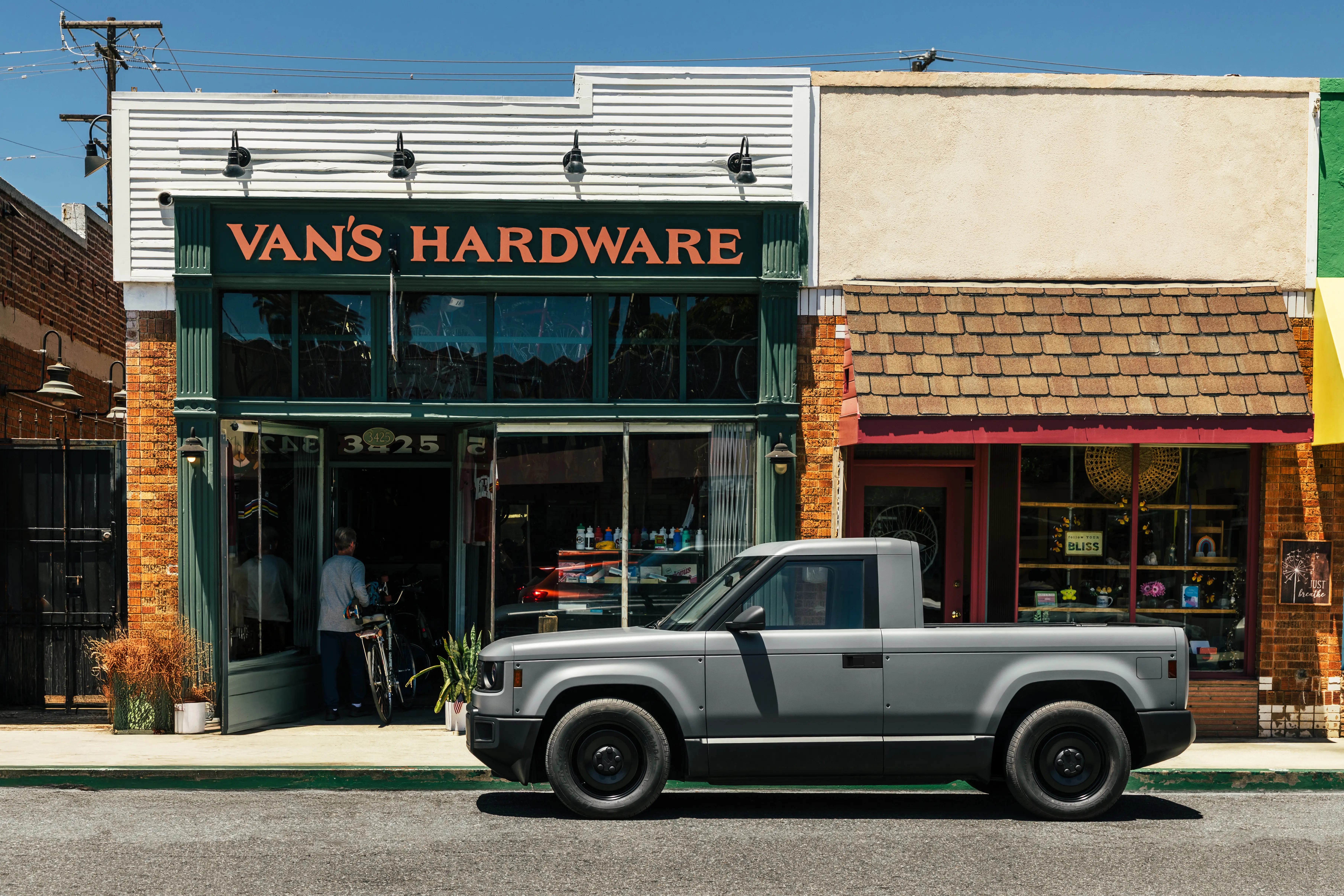 A gray Slate truck is parked outside a small business.