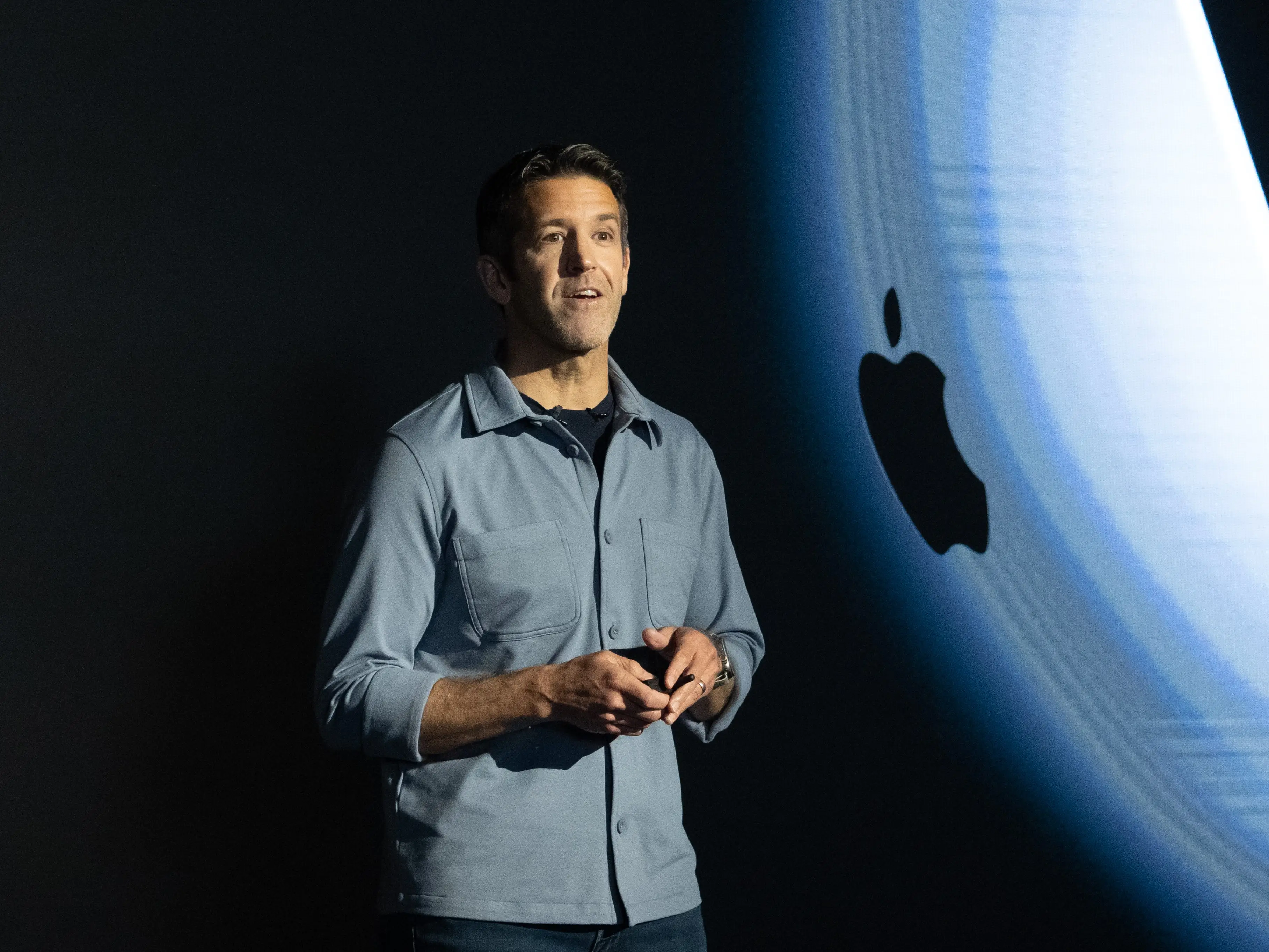 Apple's incoming CEO, John Ternus, presents onstage with an Apple logo in the background.