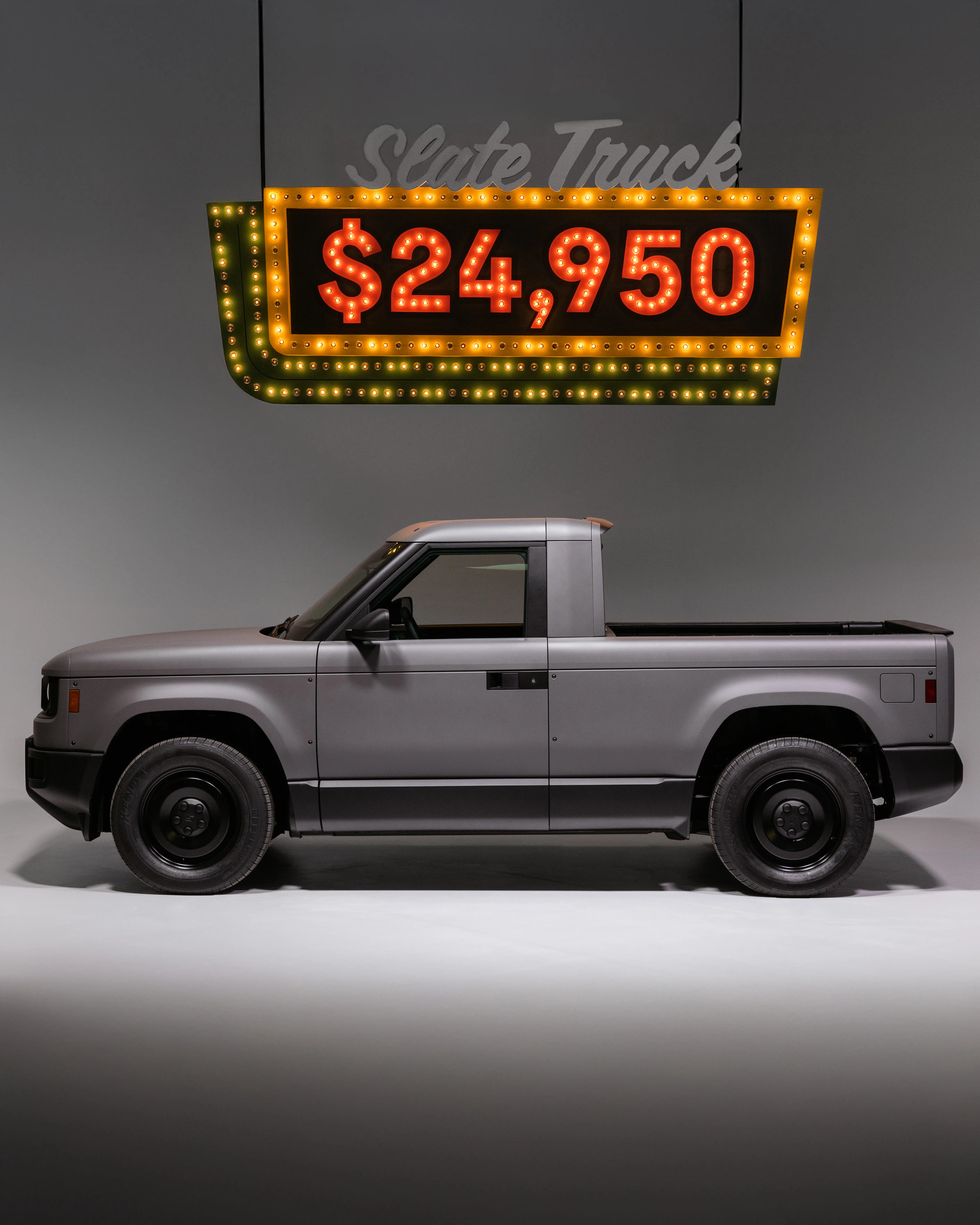 A Slate Truck is parked underneath a marquee sign with its $24,950 starting price.