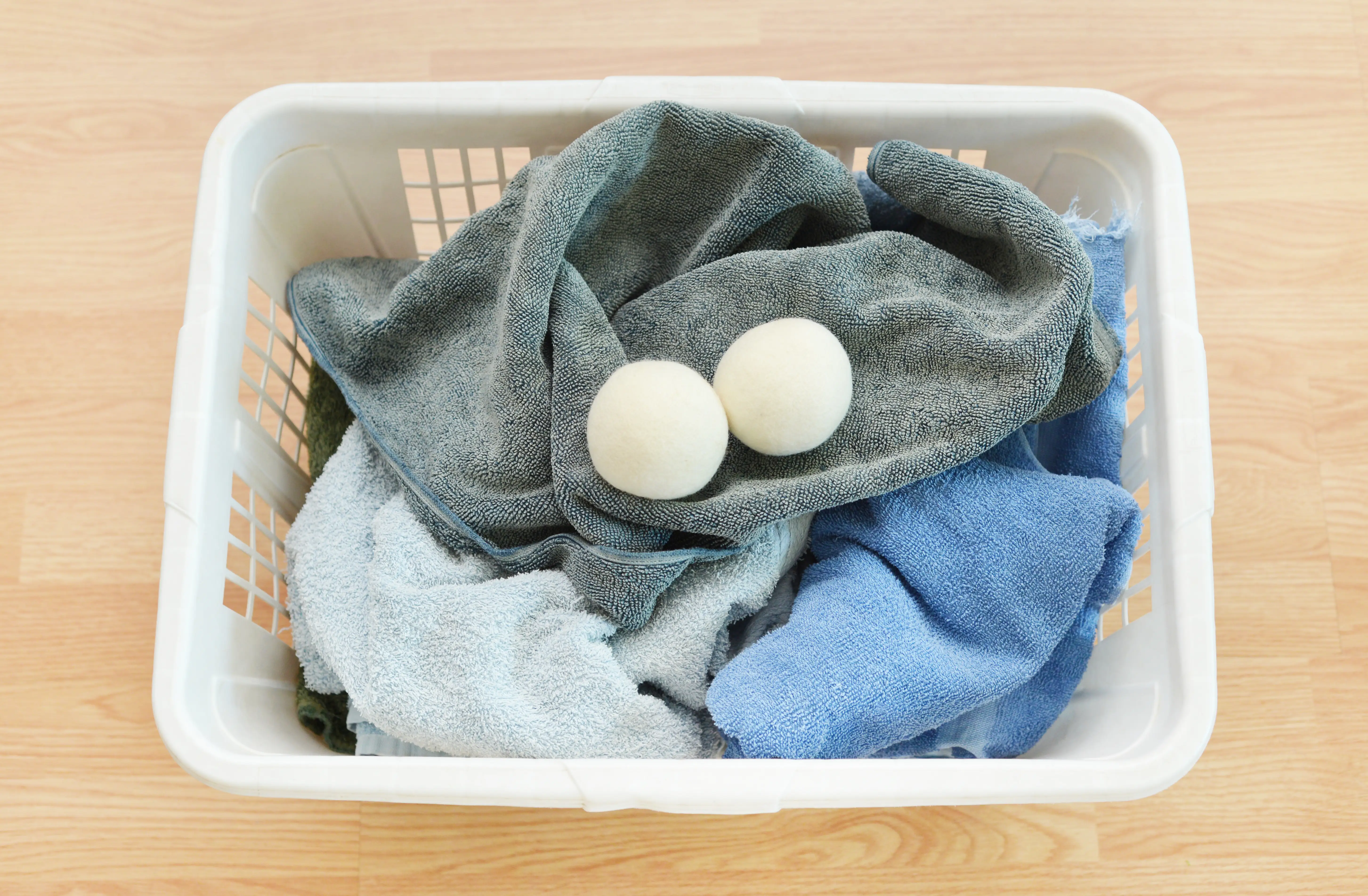 Two white dryer balls in a laundry basket filled with towels