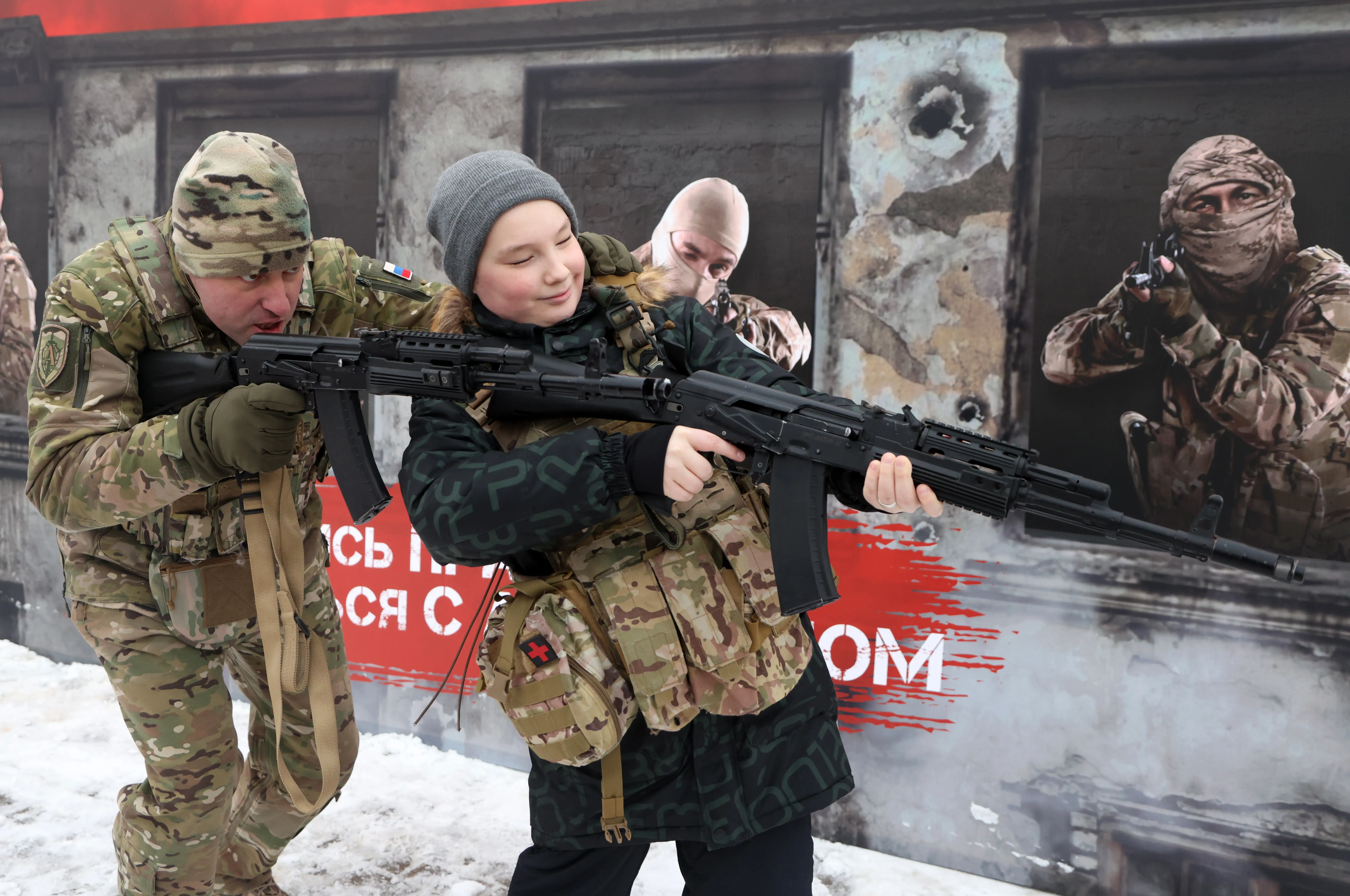 An FSB employee teaches a boy how to hold a rifle.