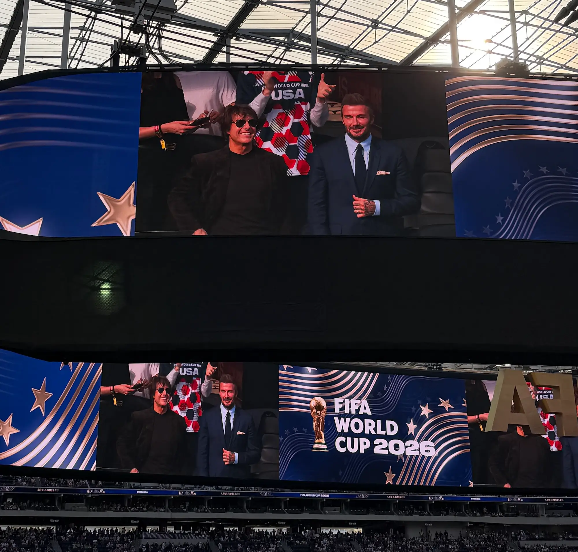 Stadium video boards show Tom Cruise and David Beckham alongside FIFA WORLD CUP 2026 graphics.
