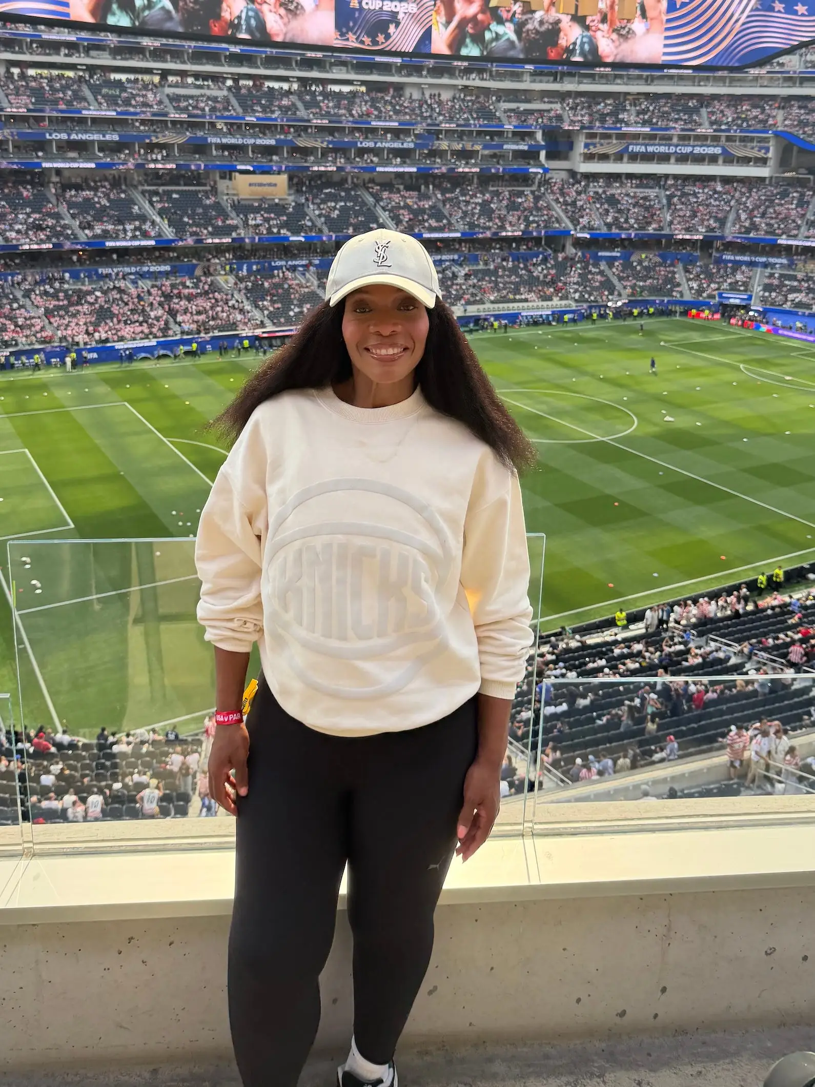 Person standing in a stadium suite overlooking a soccer field during a FIFA World Cup 2026 event.