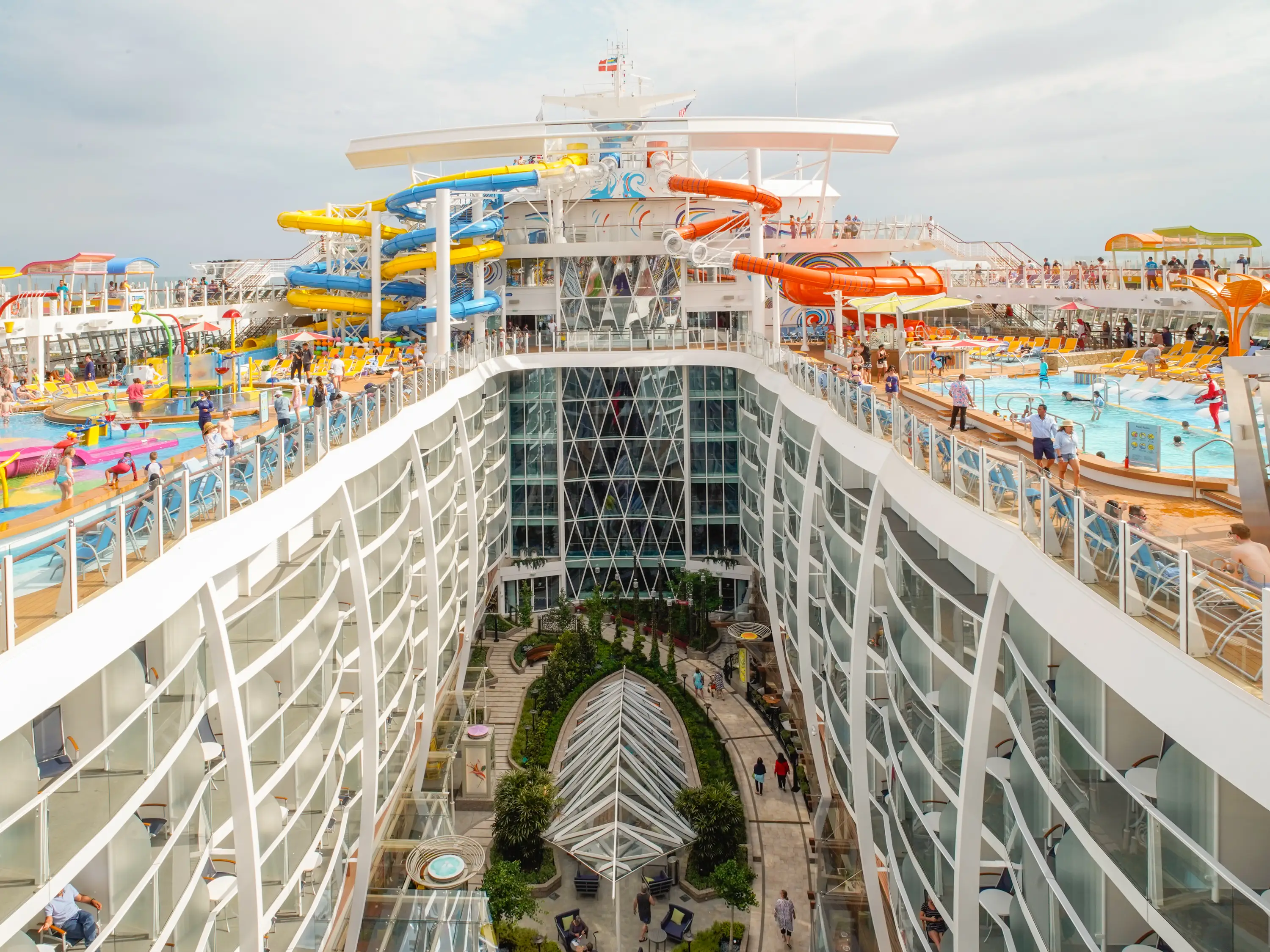 Royal Caribbean's Wonder of the Seas cruise ship seen from the top deck with pools on either side of vibrant water slides,
