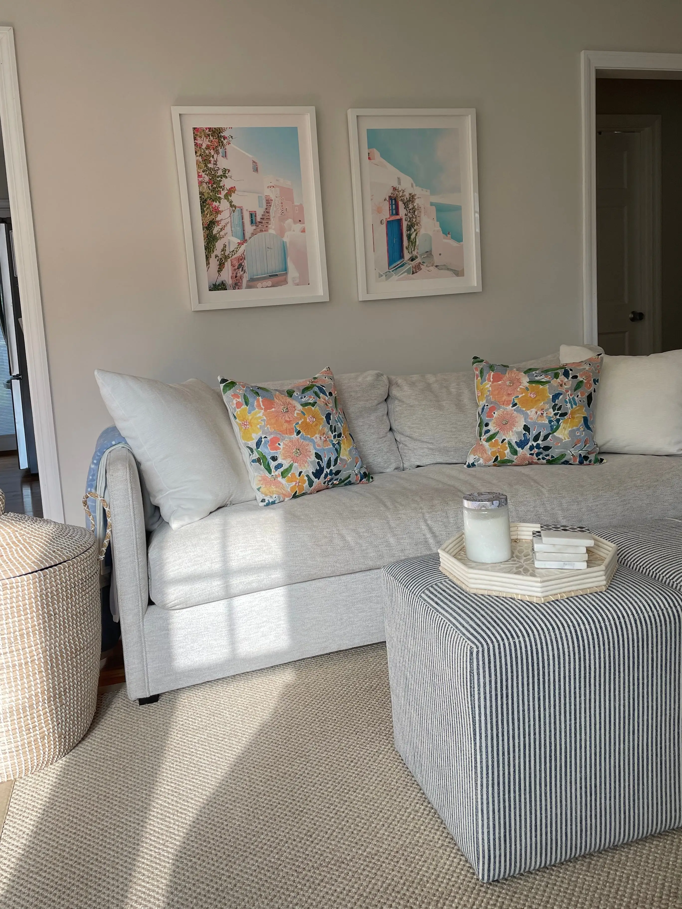 A living room with a couch against a small wall. Two doorways frame the wall, one leading to a kitchen.