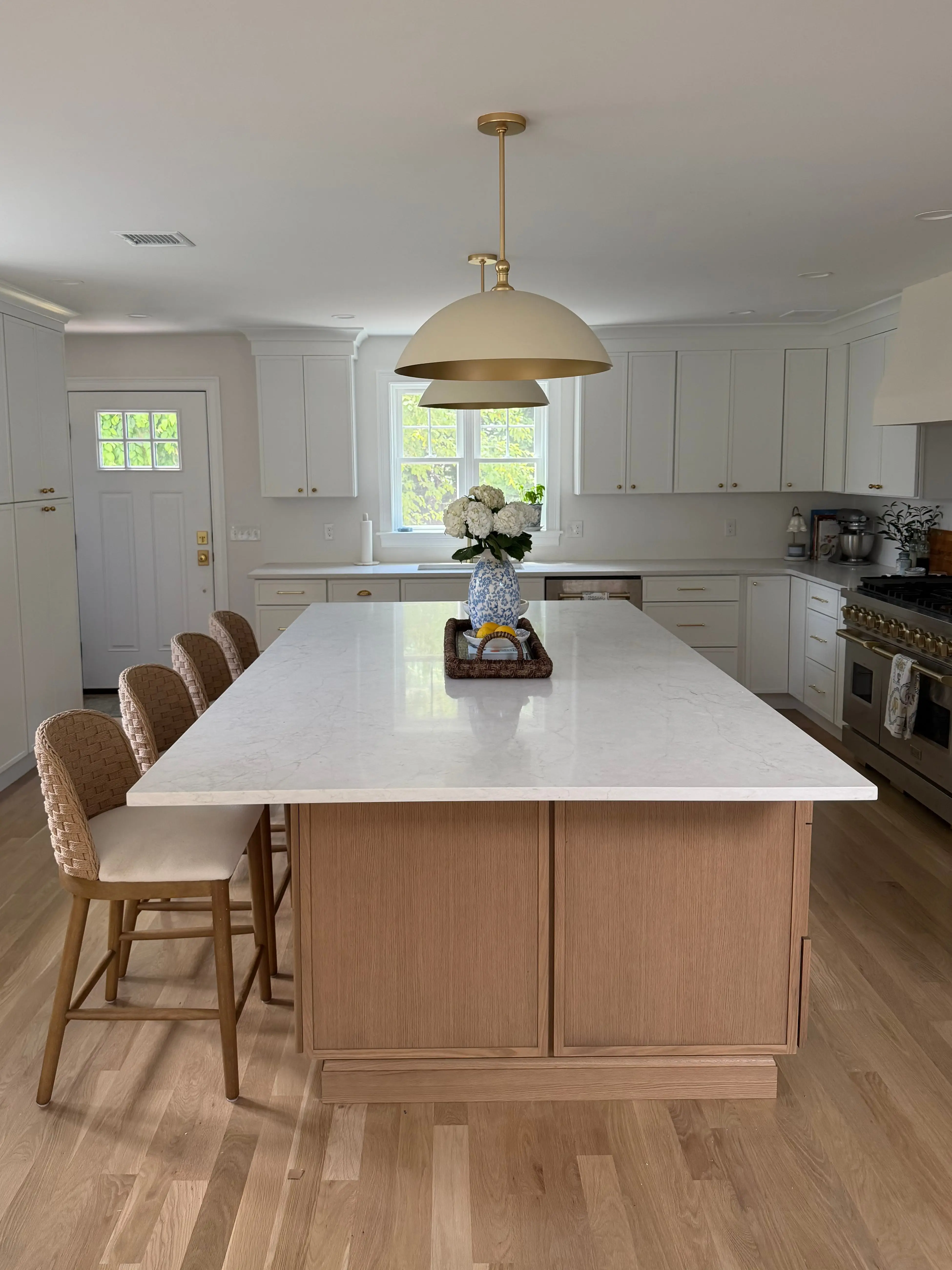 A kitchen with a large island, white cabinets, and a double oven.