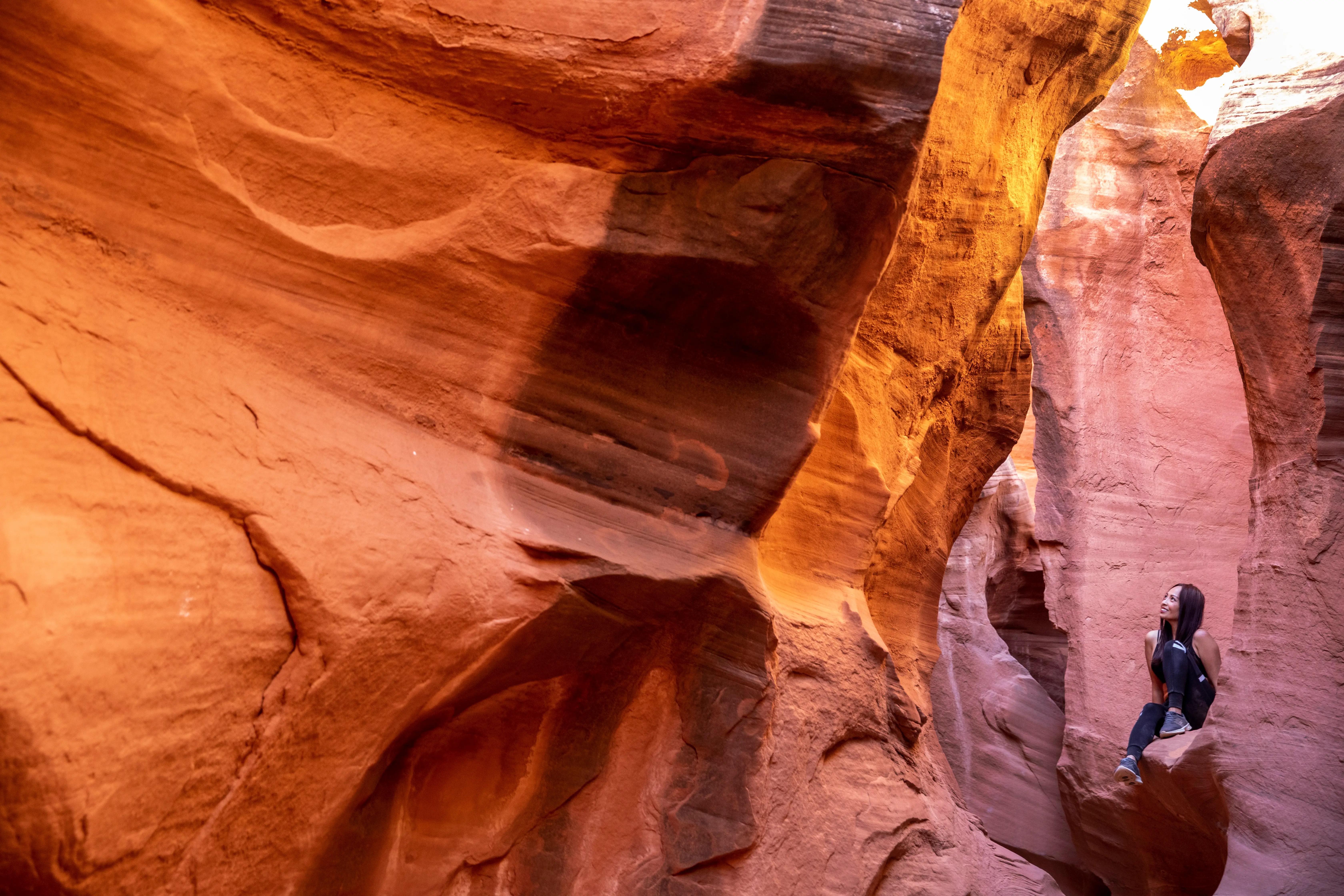 Woman surrounded by reddish rocks in Peek-A-Boo Slot Canyon in Utah