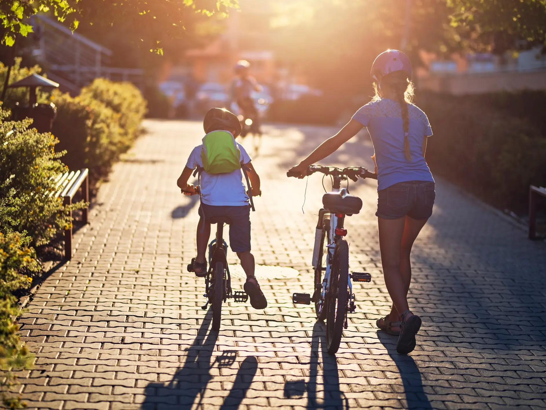 Two children riding their bikes on a path, wearing helmets.