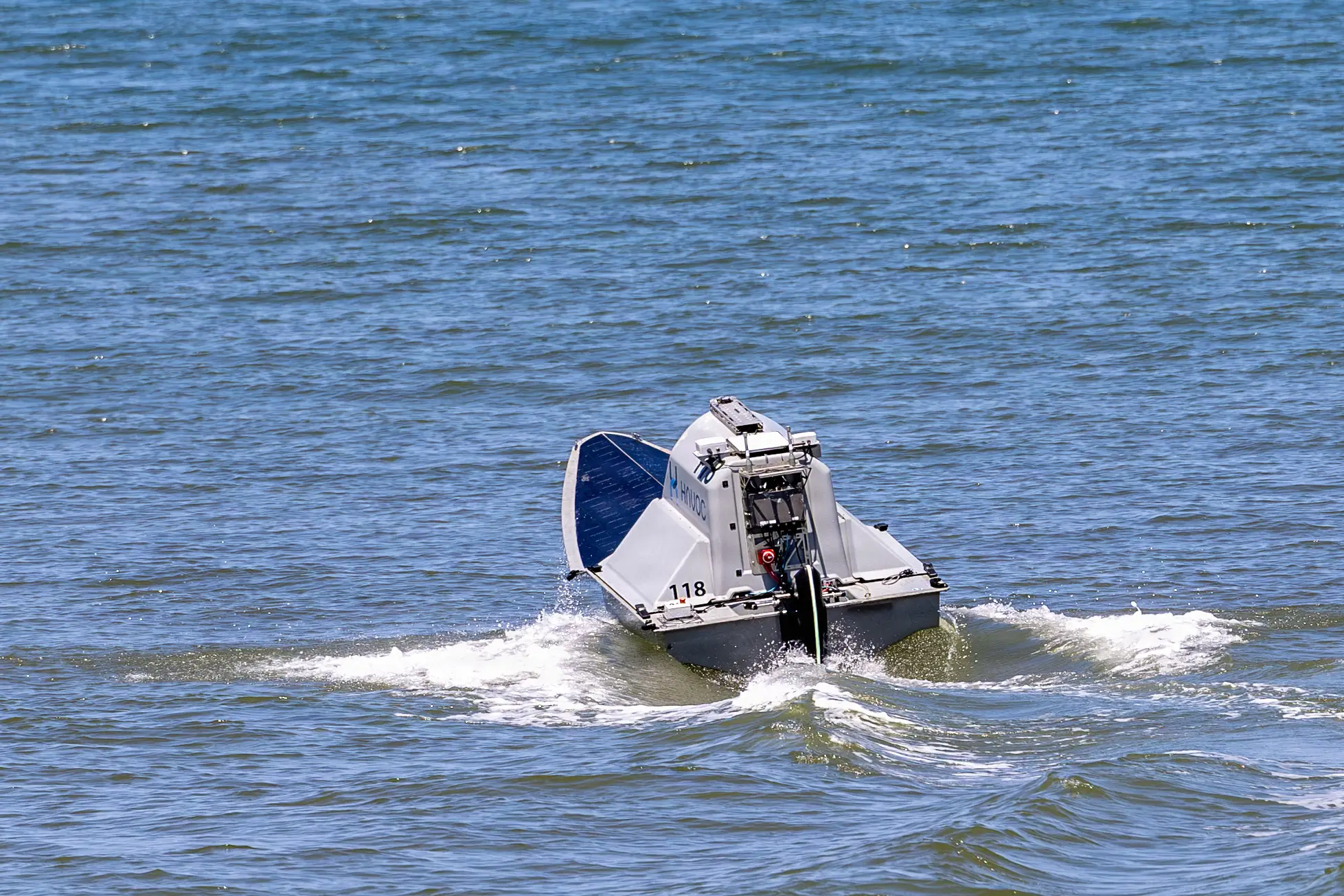A drone boat sails in the blue ocean.
