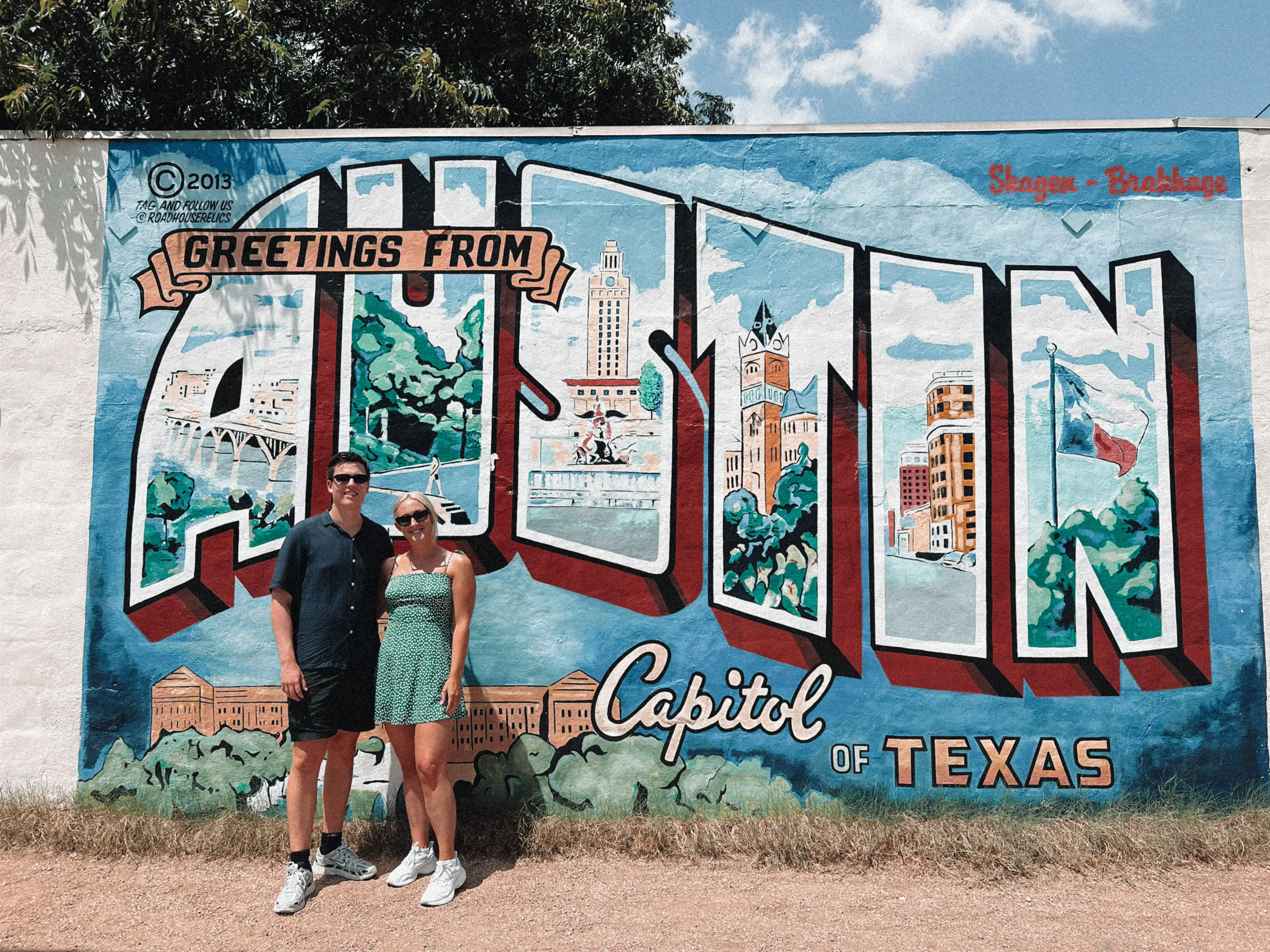 Amanda and her boyfriend pose in front of a mural that reads 