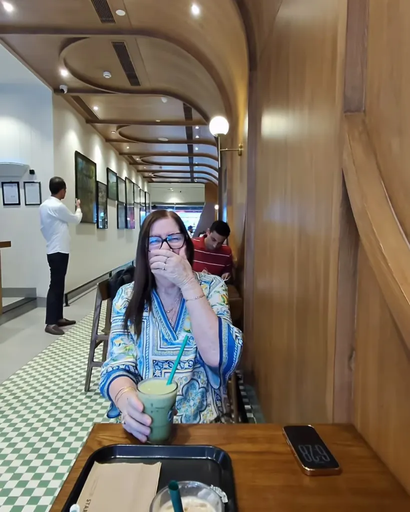 Jenny Slatten from 90 Day Fiancé holding a drink and covering her mouth, with a man in the background.