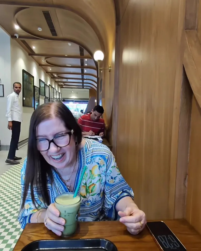 Jenny Slatten laughing with a drink in a cafe.